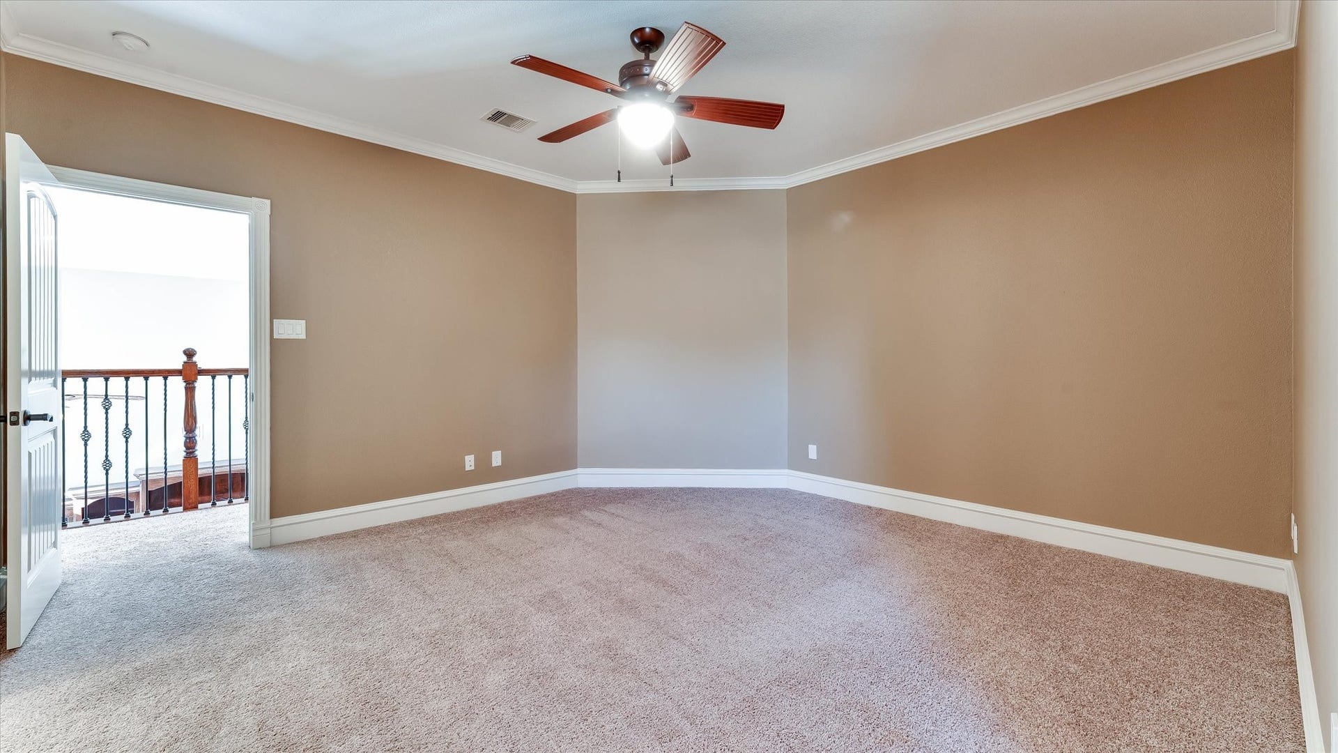 8071 Stacy Diane Drive, Montgomery, TX 77316 This room features soft beige walls, plush carpet, and a ceiling fan, offering a cozy and comfortable space. The open door leads to a hallway with a decorative railing, adding a touch of elegance.