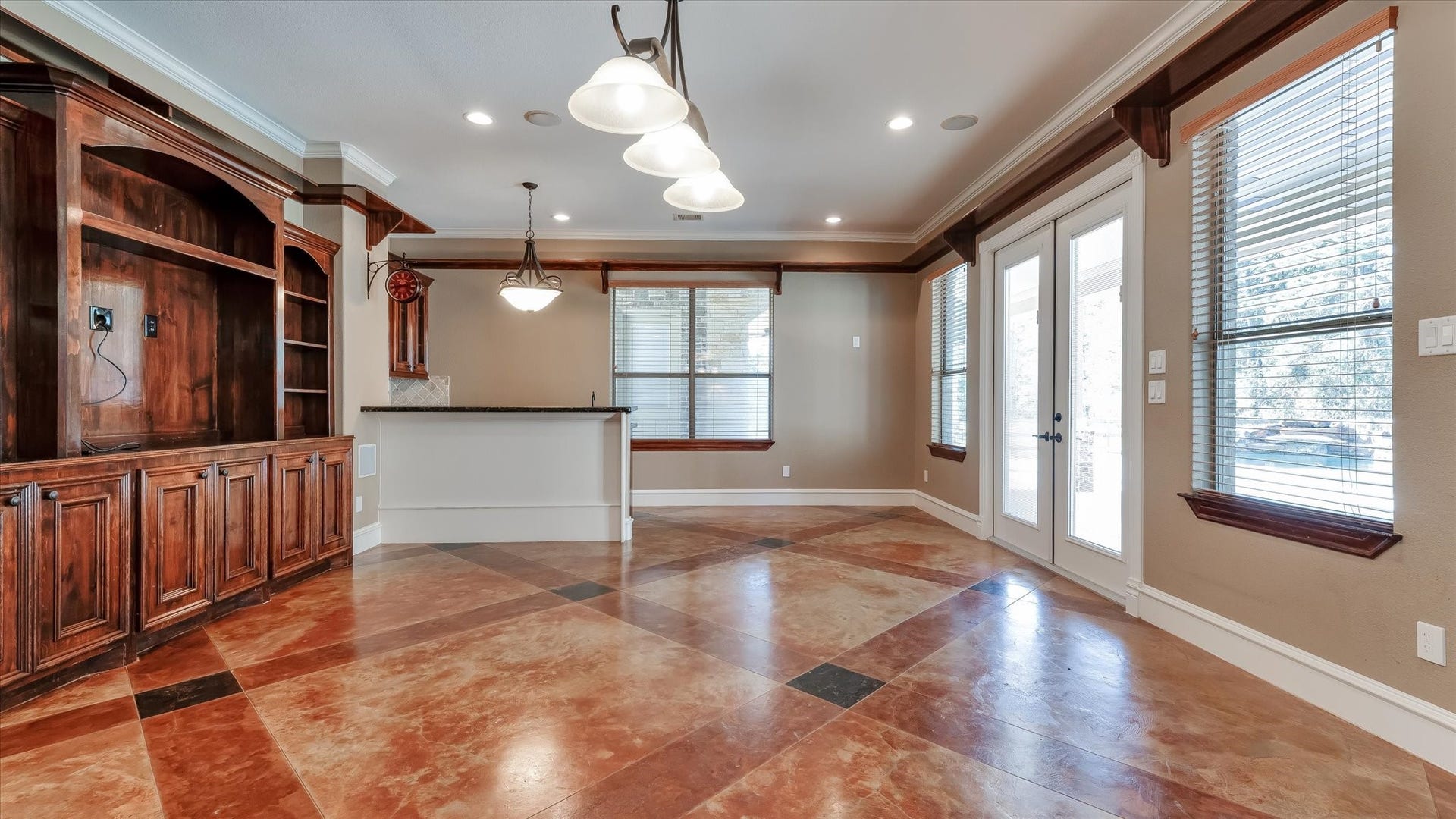 8071 Stacy Diane Drive, Montgomery, TX 77316 This spacious room features elegant tile flooring, a built-in wooden entertainment unit, and large windows for natural light. French doors open to the outdoors, and a stylish light fixture adds charm. Perfect for living or entertaining.