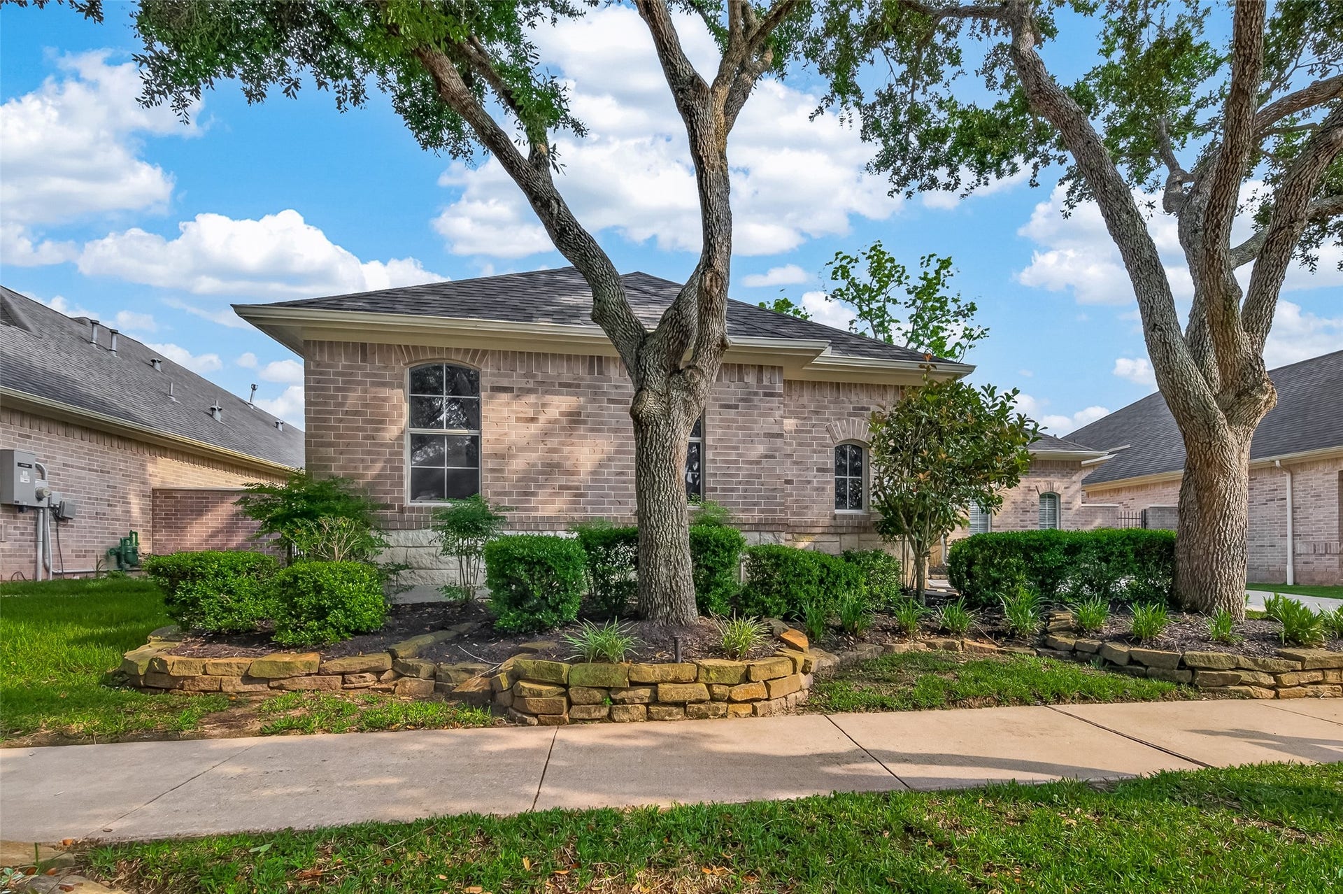 10106 Lost Hollow Lane, Missouri City, TX 77459 Charming brick home with well-maintained landscaping, featuring mature trees and neatly trimmed shrubs. The property offers a serene atmosphere and great curb appeal.