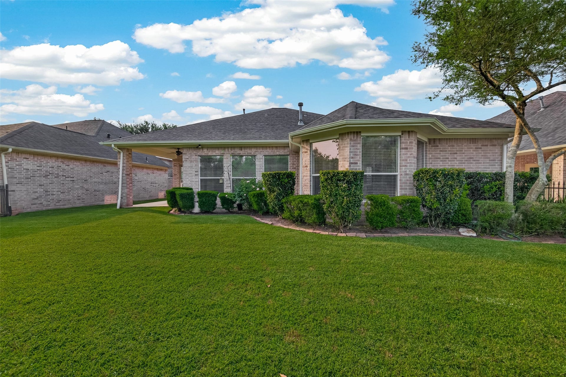 10106 Lost Hollow Lane, Missouri City, TX 77459 Charming single-story brick house with a well-maintained backyard. Features a covered patio, lush green lawn, and neatly trimmed hedges, perfect for outdoor relaxation.