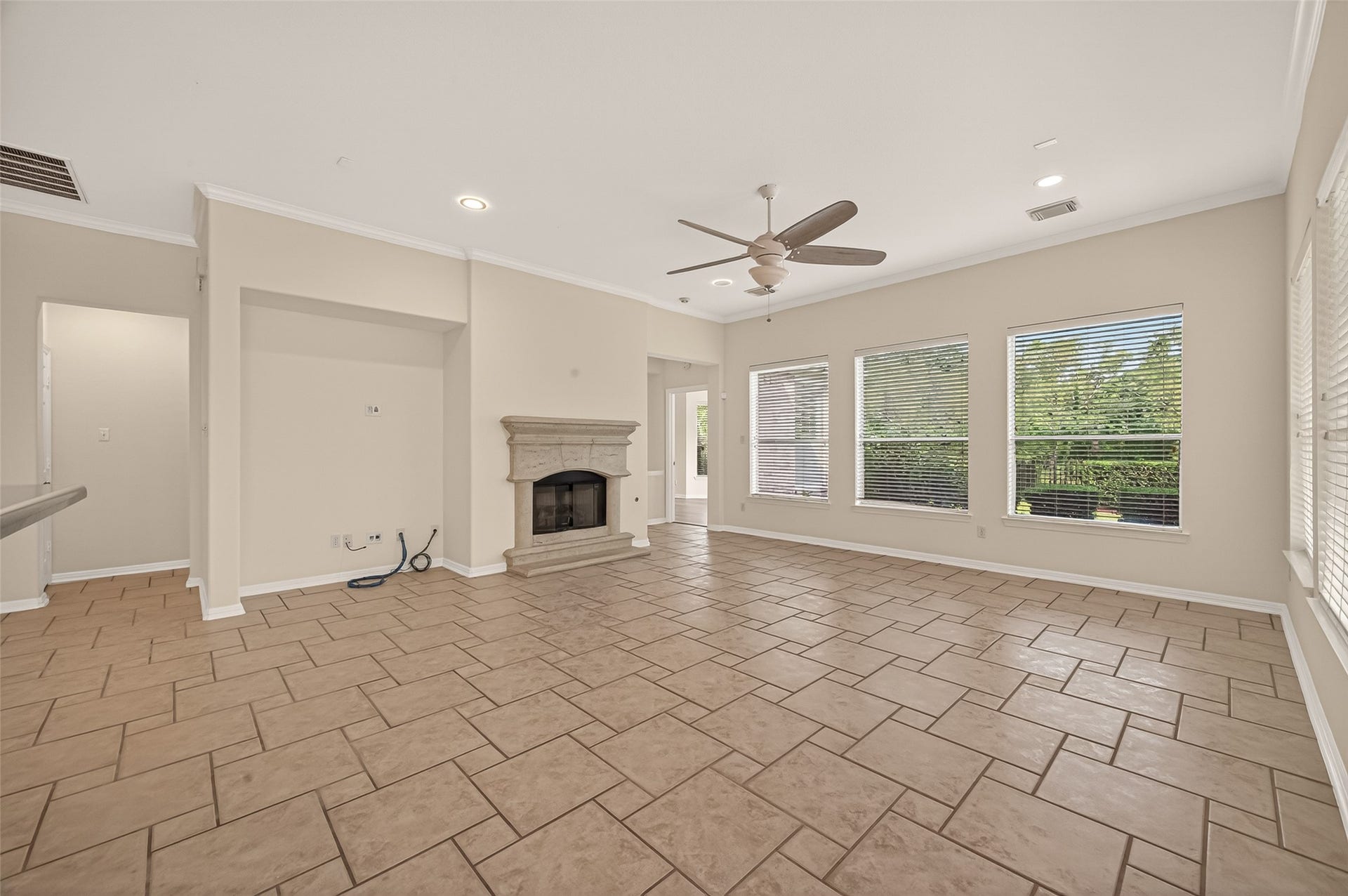 10106 Lost Hollow Lane, Missouri City, TX 77459 This spacious living room features a tiled floor, neutral walls, and a ceiling fan. Large windows provide ample natural light, and there's a cozy fireplace for added warmth. The open layout connects seamlessly to adjoining rooms.