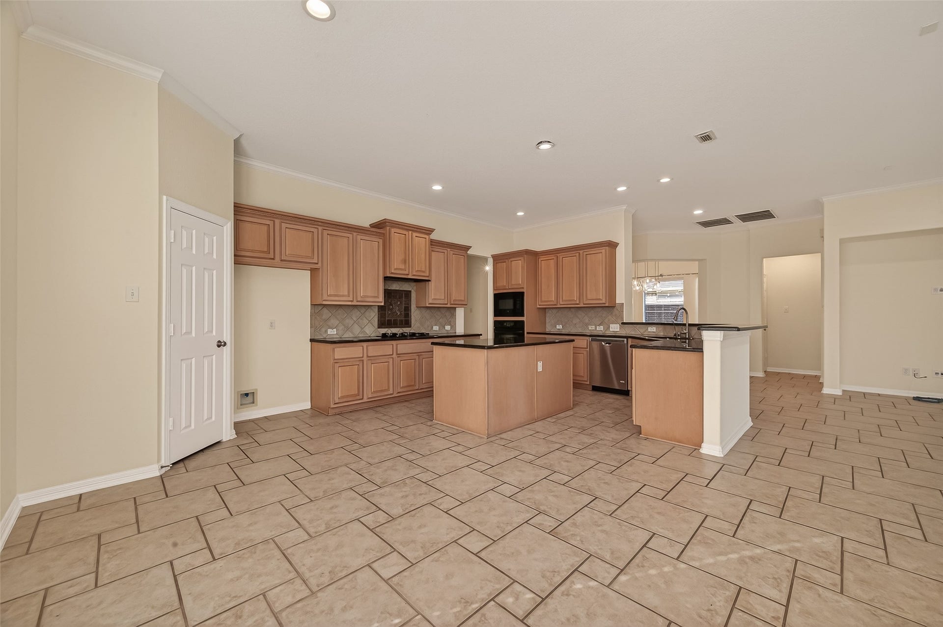 10106 Lost Hollow Lane, Missouri City, TX 77459 This spacious kitchen features light wood cabinetry, an island, and modern appliances. The open layout and tile flooring offer a bright and functional space, ideal for cooking and entertaining.
