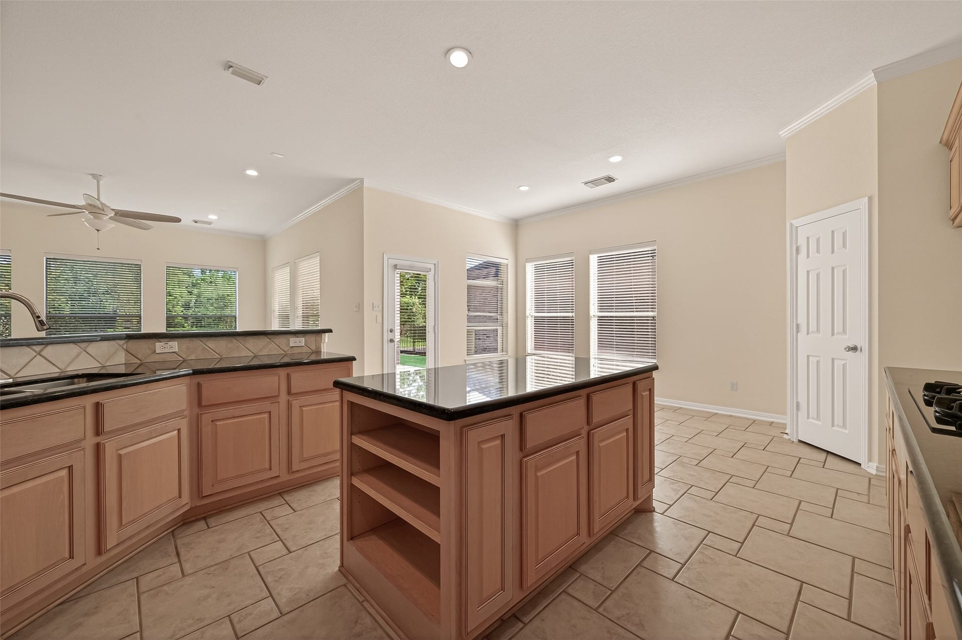 10106 Lost Hollow Lane, Missouri City, TX 77459 This spacious kitchen features light wood cabinetry, a large central island with granite countertops, and tile flooring. Ample natural light pours in through multiple windows, creating an inviting and bright atmosphere.