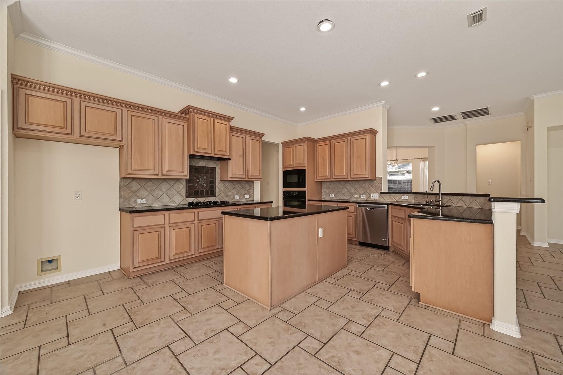 10106 Lost Hollow Lane, Missouri City, TX 77459 Spacious kitchen with light wood cabinetry, granite countertops, a central island, and modern appliances. The tile flooring and recessed lighting add a sleek touch, perfect for cooking and entertaining.