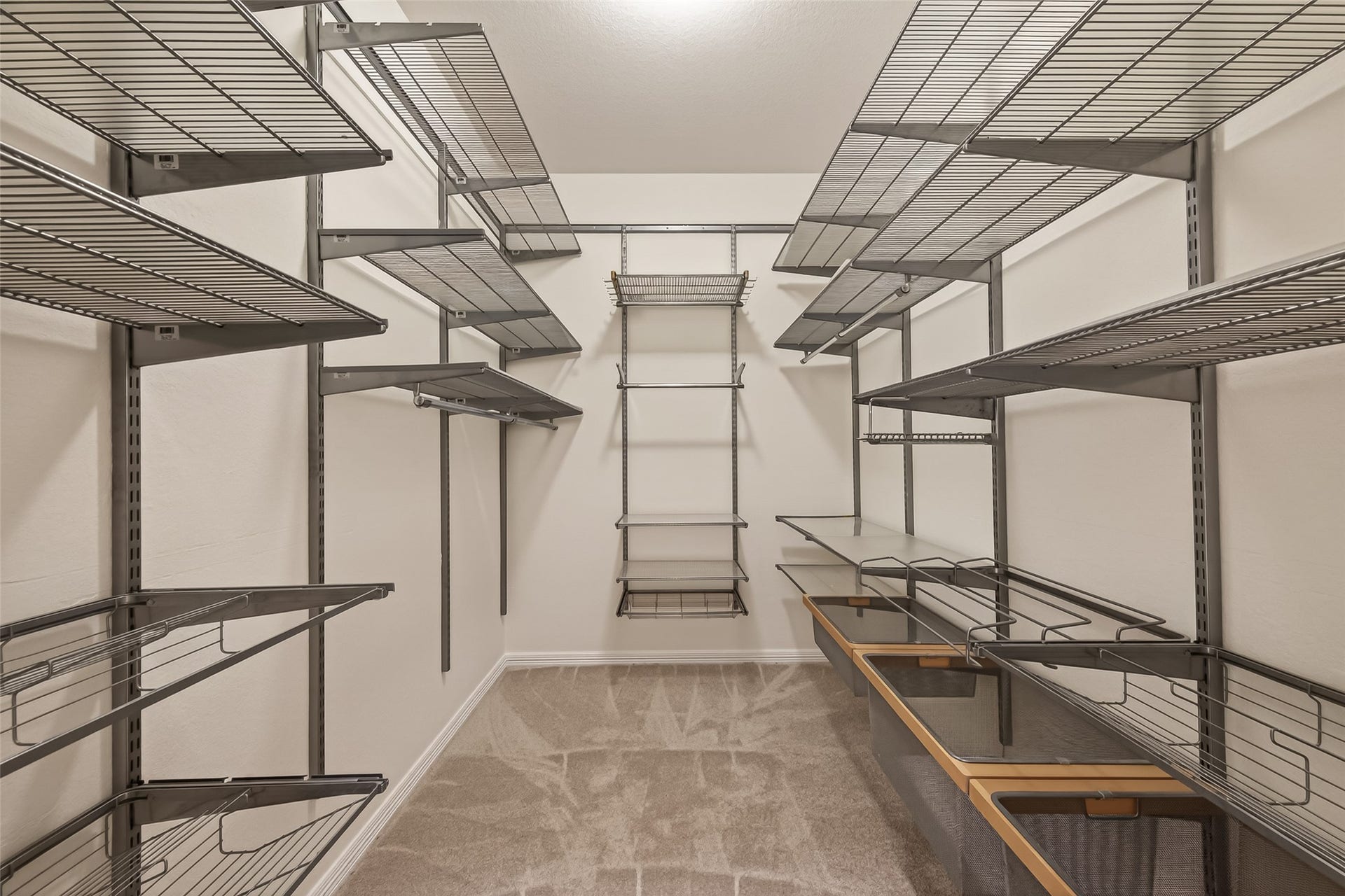 10106 Lost Hollow Lane, Missouri City, TX 77459 Spacious walk-in closet with ample shelving and storage options, featuring adjustable metal racks and a clean, carpeted floor. Ideal for organizing clothing and accessories.Primary closet 1.