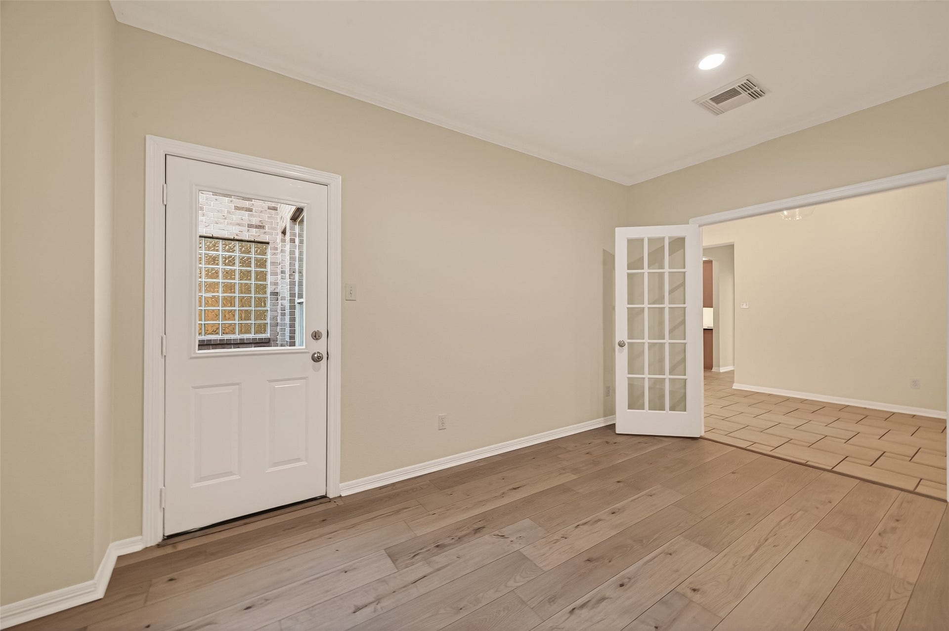 10106 Lost Hollow Lane, Missouri City, TX 77459 This room features warm wood flooring, a neutral color palette, and a door with a window leading outside. French doors open to a tiled space, enhancing natural light and connectivity.