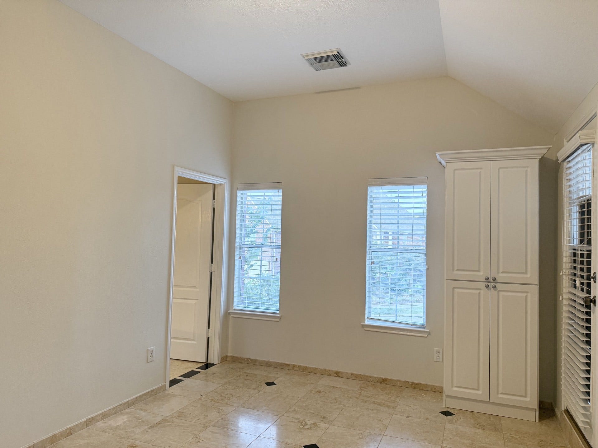 Primary bedroom with soaring ceiling and a private balcony, beautiful tile flooring.