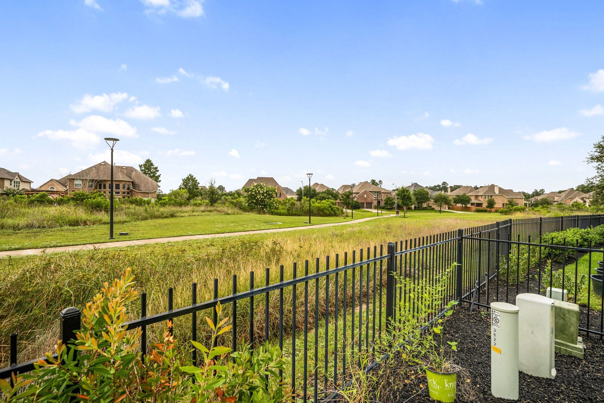 3622 Sage Hollow Drive, Spring, TX 77386 A view along the back wrought-iron fence line highlights the neighborhood's open-space layout, offering premium views of the surrounding community walking paths and natural landscape.