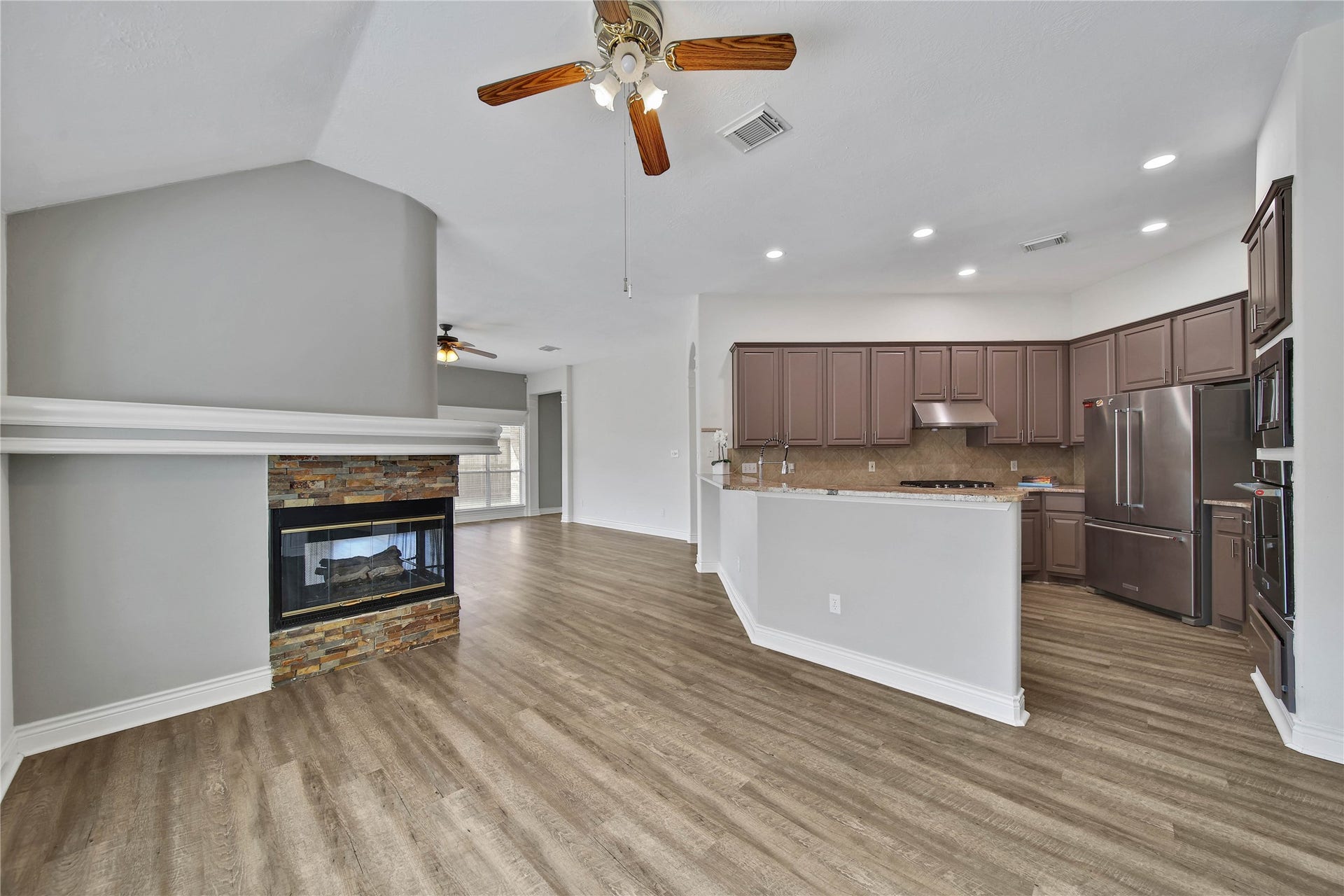 5918 Greenway Manor Lane, Spring, TX 77373 Open kitchen adjoining living area featuring a cozy fireplace, ideal for everyday living and entertaining.