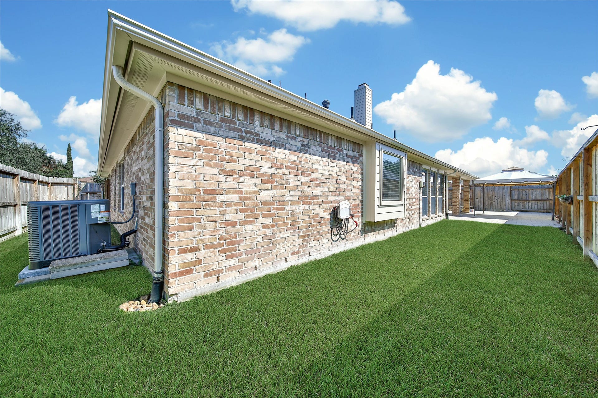 5918 Greenway Manor Lane, Spring, TX 77373 Fenced backyard featuring a lush lawn and a concrete outdoor shaded patio, offering space for outdoor dining, gardening, or relaxing.