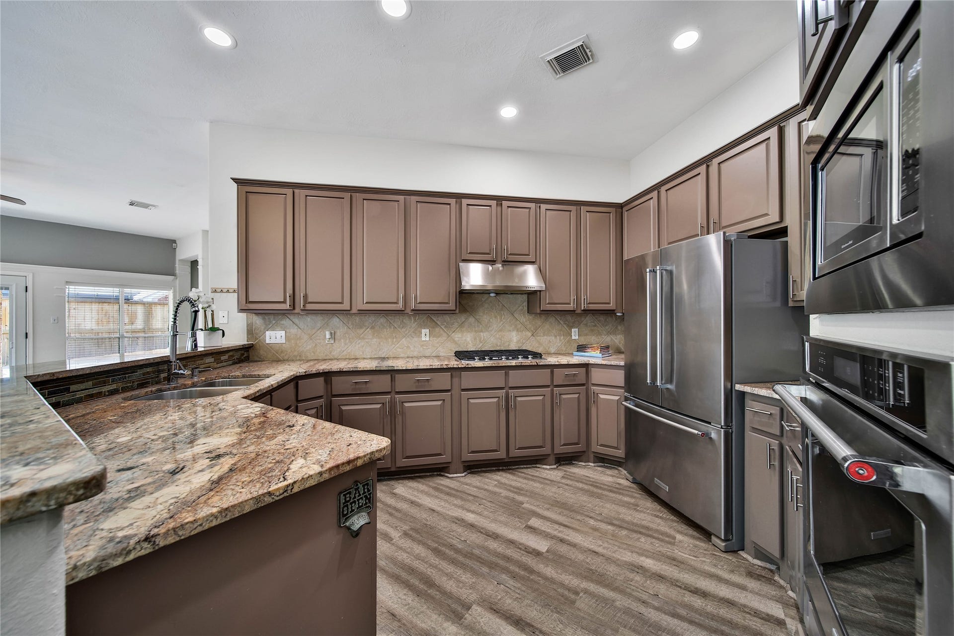 5918 Greenway Manor Lane, Spring, TX 77373 Spacious kitchen with abundant cabinetry, expansive countertops, gas cooktop with stainless steel appliances and raised breakfast bar overlooks the adjoining living area, keeping spaces connected for easy entertaining.
