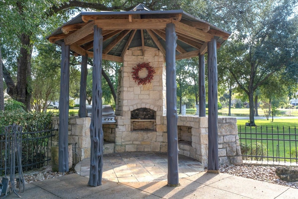 8514 Haven Way, Tomball, TX 77375 This covered outdoor kitchen features a grill, a stone pizza oven, and counter space, ideal for weekend cookouts and entertaining.
