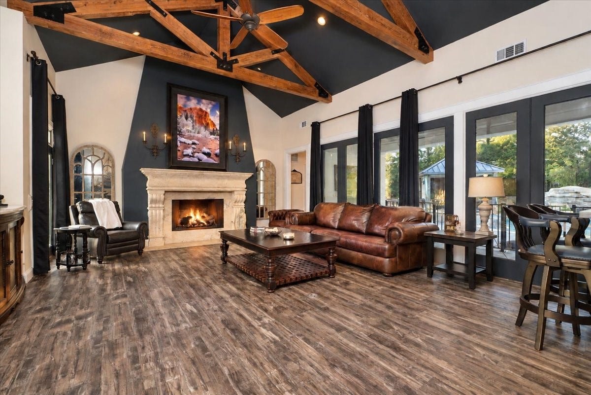 8514 Haven Way, Tomball, TX 77375 Gather around the fireplace on cool evenings! The living room boasts exposed wood beams and new luxury vinyl plank flooring, with French doors leading seamlessly out to the patio and pool.