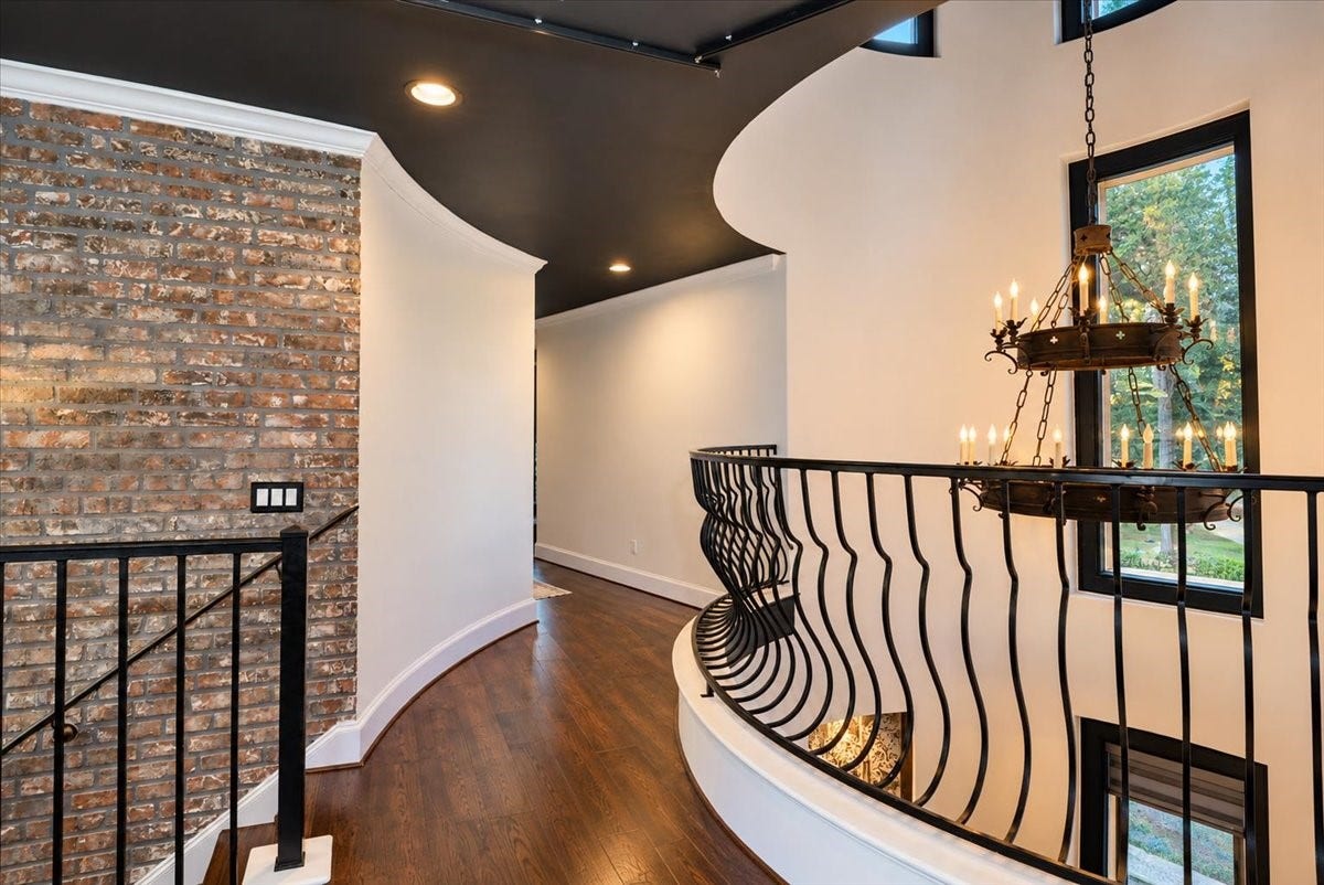 8514 Haven Way, Tomball, TX 77375 A charming upstairs landing with natural light, a statement chandelier, and a curved railing with views down to the entry.
