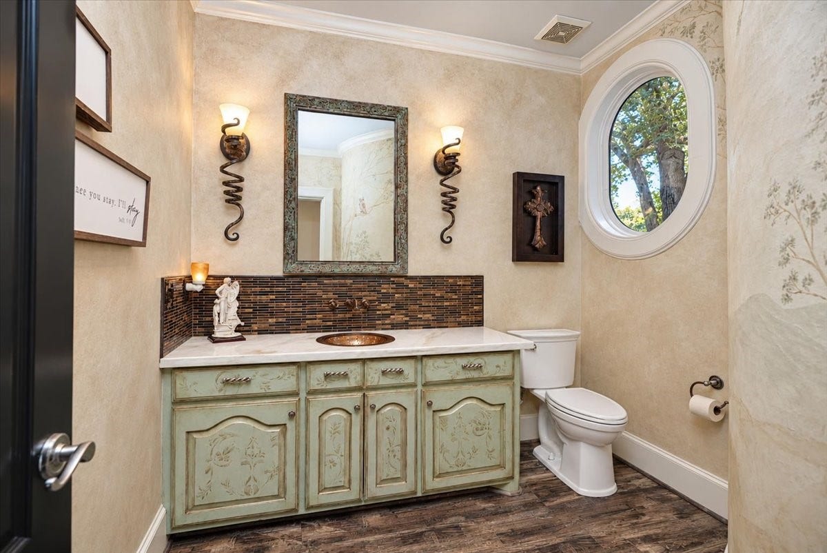 8514 Haven Way, Tomball, TX 77375 A thoughtful touch for guests, this half bath offers custom wall finishes, crown molding, and natural light from a charming oval window.