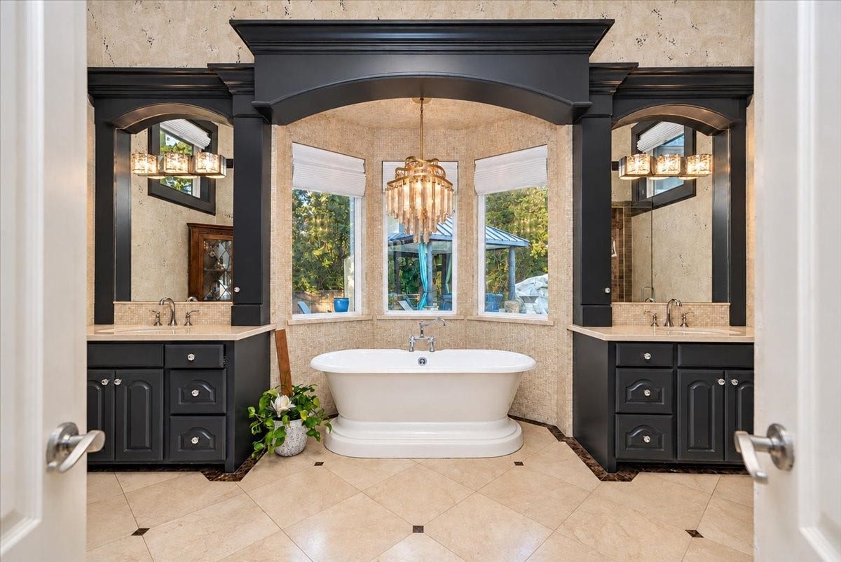 8514 Haven Way, Tomball, TX 77375 Unwind after a long day in this primary bath, where a freestanding tub sits beneath a statement chandelier. Dual vanities with ample cabinet storage and generous counter space on each side make mornings easy.