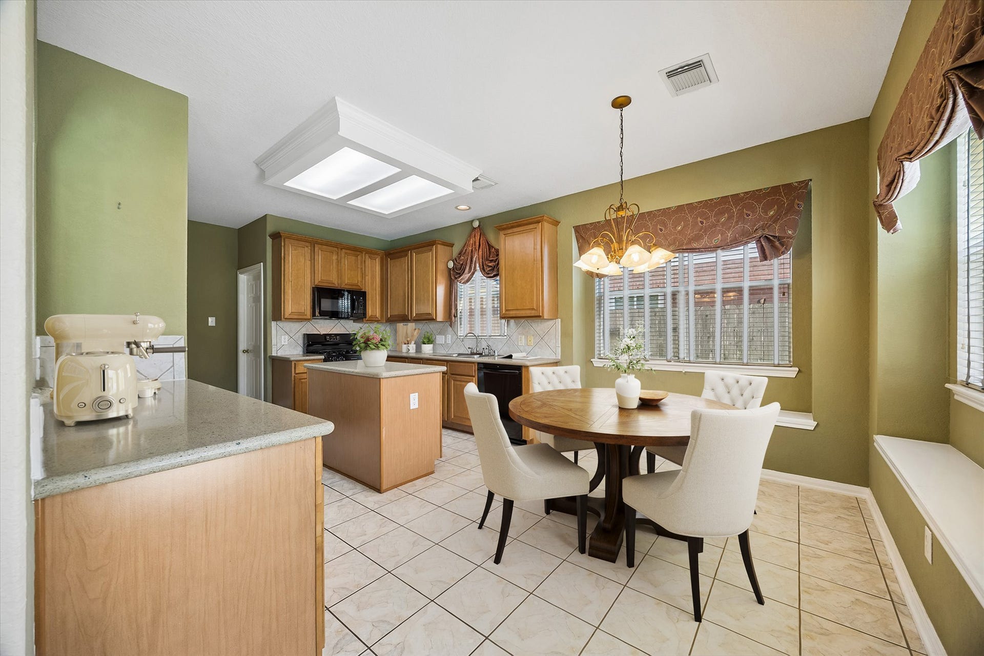 2843 Five Oaks Drive, Missouri City, TX 77459 Bright and open, the kitchen and breakfast area flow together beautifully with tile flooring, designer paint, quartz countertops, classic wood cabinetry, a center island and built-in window seats that make casual meals feel right at home.