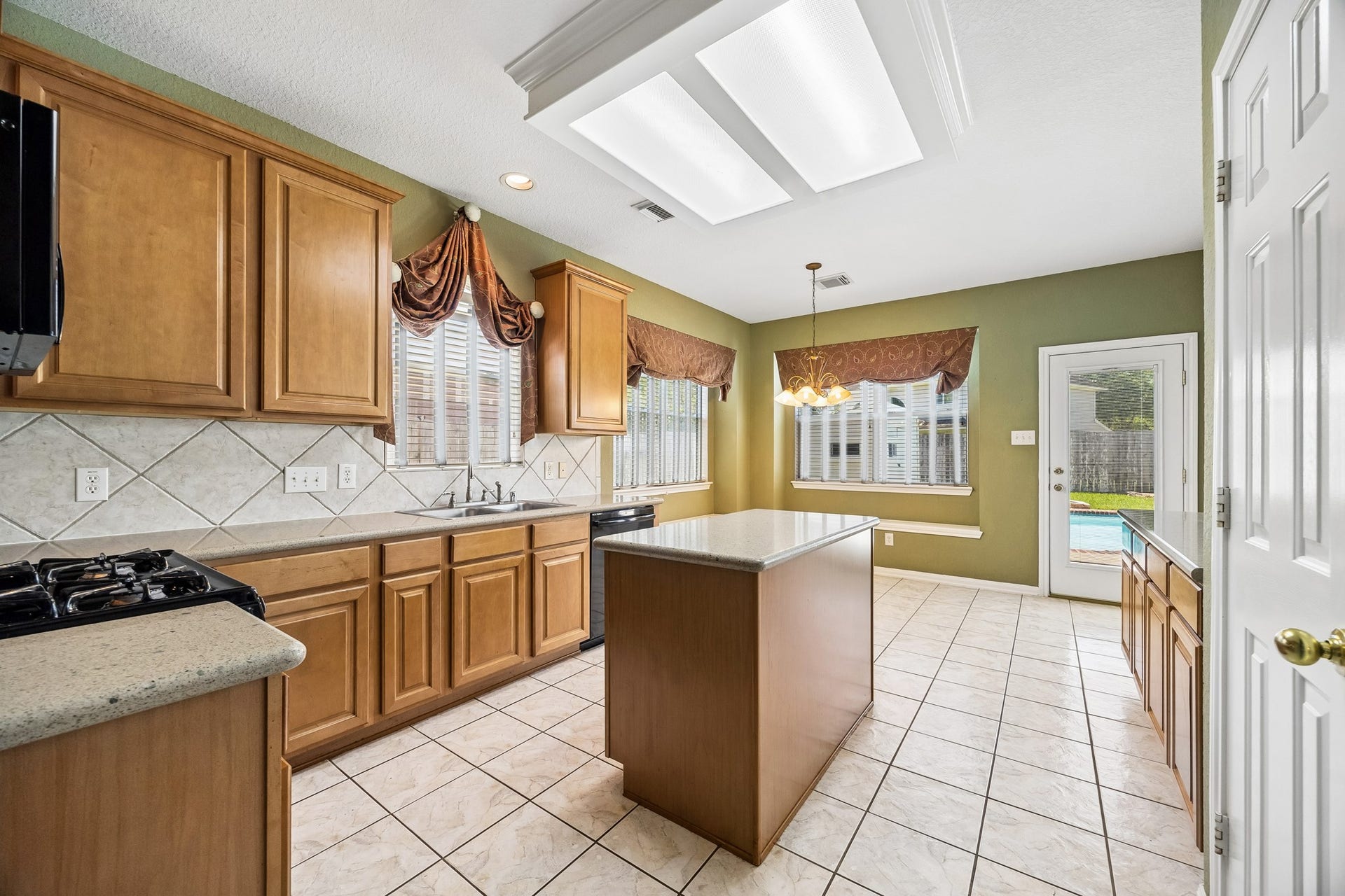 2843 Five Oaks Drive, Missouri City, TX 77459 This spotless kitchen is ready for busy mornings and weeknight dinners with quartz counters, classic wood cabinetry, tile backsplash, sleek black appliances and plenty of prep space with a large center island.