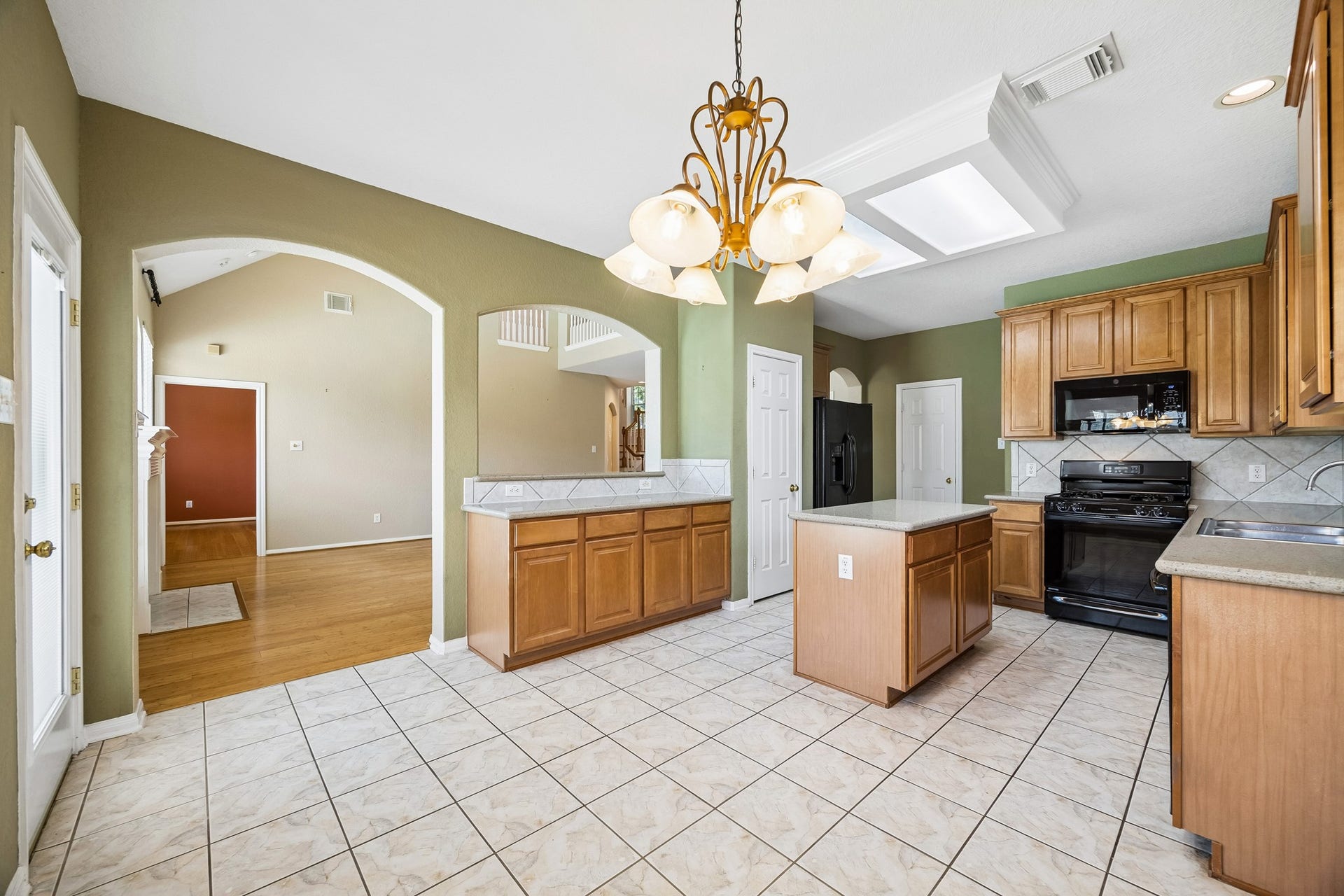 2843 Five Oaks Drive, Missouri City, TX 77459 Arched openings and the pass-through bar keep the kitchen connected to the family room, while quartz counters, classic cabinetry and bright overhead lighting make the space both practical and welcoming.