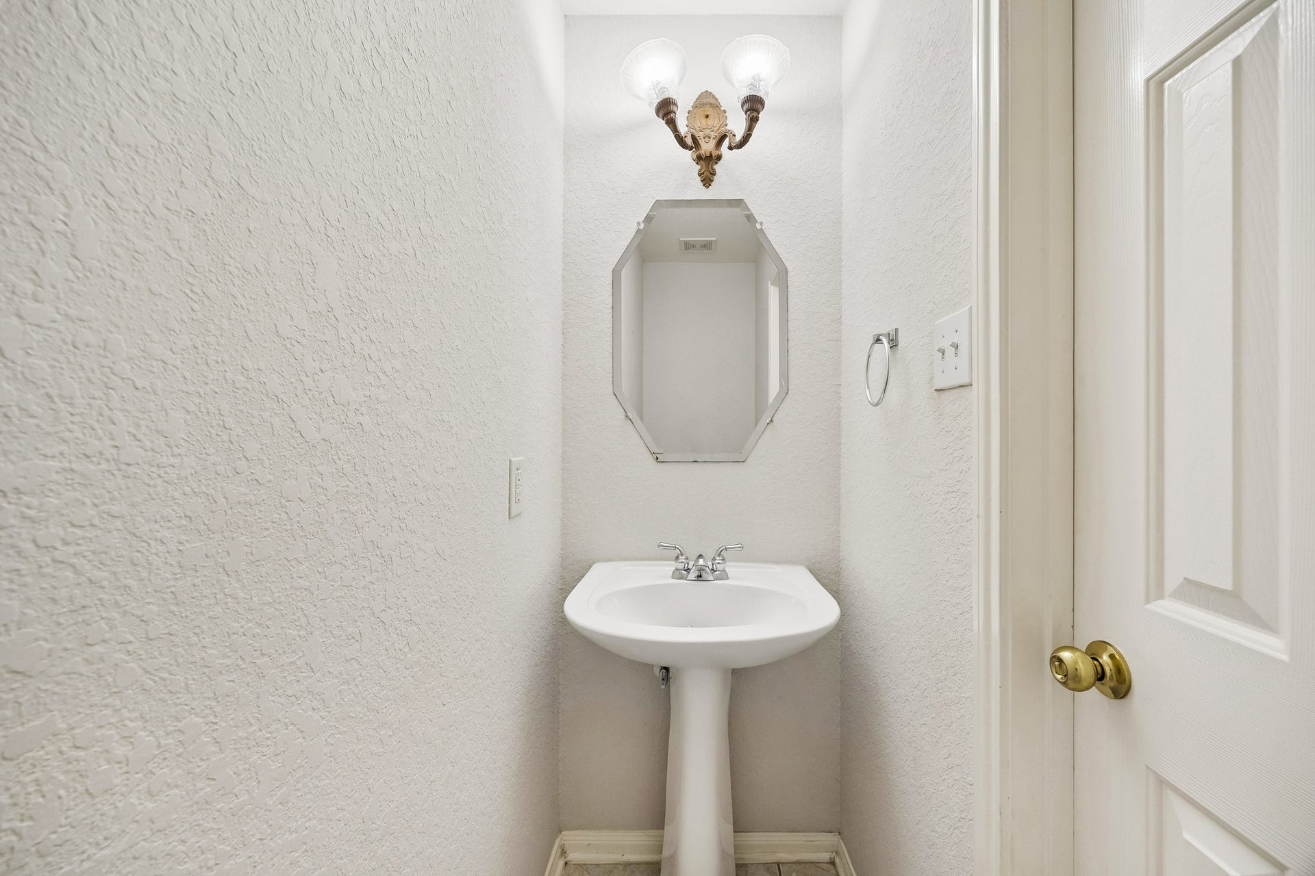 2843 Five Oaks Drive, Missouri City, TX 77459 A convenient first floor powder bath is ready for guests with a classic pedestal sink, bright vanity lighting and an easy location just off the main living areas.