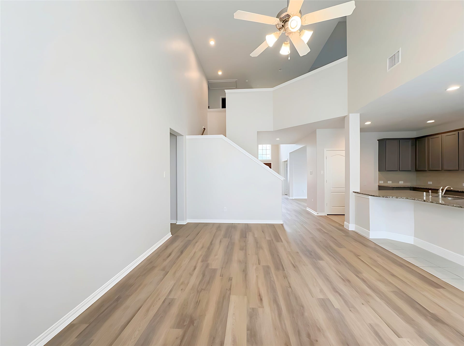 662 W Linnwood Drive, Woodbranch, TX 77357 Spacious open-concept living area with high ceilings, modern wood flooring, and abundant natural light, seamlessly connecting to a sleek kitchen with dark cabinetry and granite countertops.