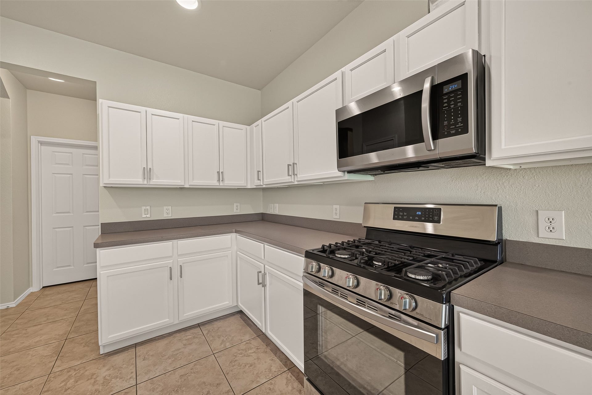 26130 Ripley Hills Drive, Richmond, TX 77406 This spacious kitchen features modern stainless steel appliances, sleek white cabinetry, and ample counter space. It opens to a bright area with windows, providing a welcoming and functional layout.