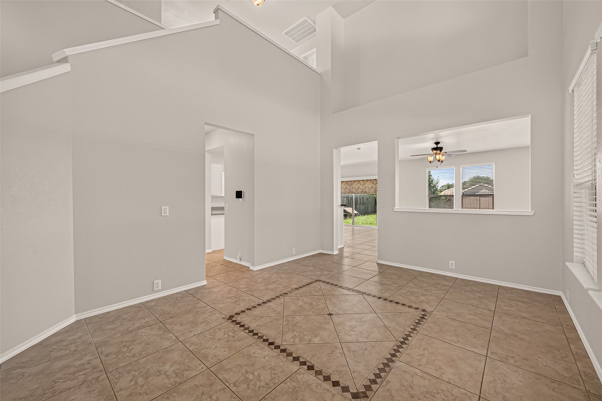 26130 Ripley Hills Drive, Richmond, TX 77406 This spacious room features high ceilings and large windows, creating a bright and airy atmosphere. The tiled floor adds a modern touch, and there's a view into the backyard, offering a seamless indoor-outdoor connection.