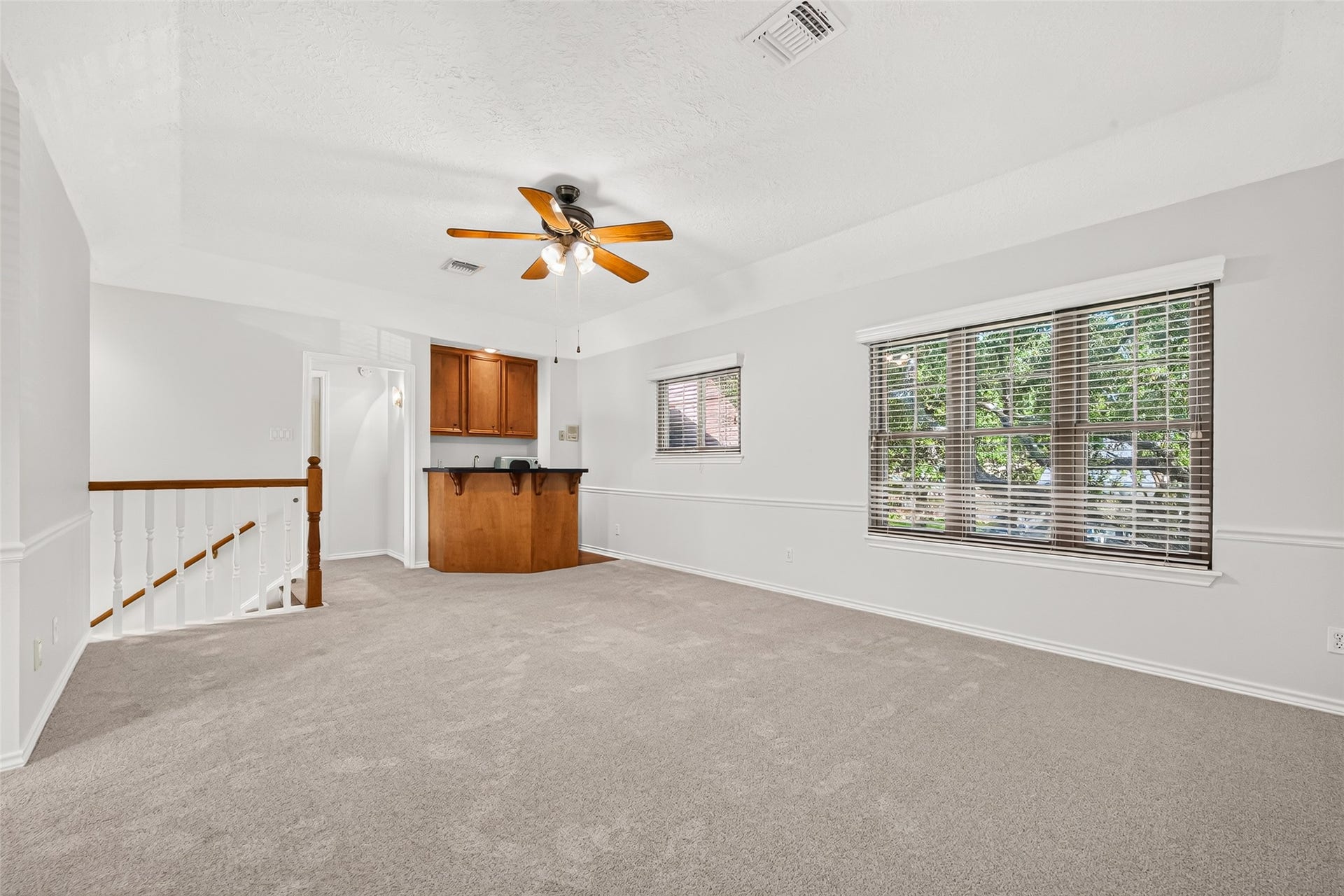 LET THE GOOD TIMES ROLL! Welcome to the spacious second-floor game rooma wonderful place for movie nights, watching the big game or enjoying a little friendly competition! Large windows with blinds overlook the tree-canopied front yard, bringing in natural light. The built-in wet bar with sink, mini refrigerator, microwave & cabinetry makes keeping drinks and snacks nearby a breeze. With plenty of room for comfortable seating, a gaming area or entertainment center, the possibilities are endless!