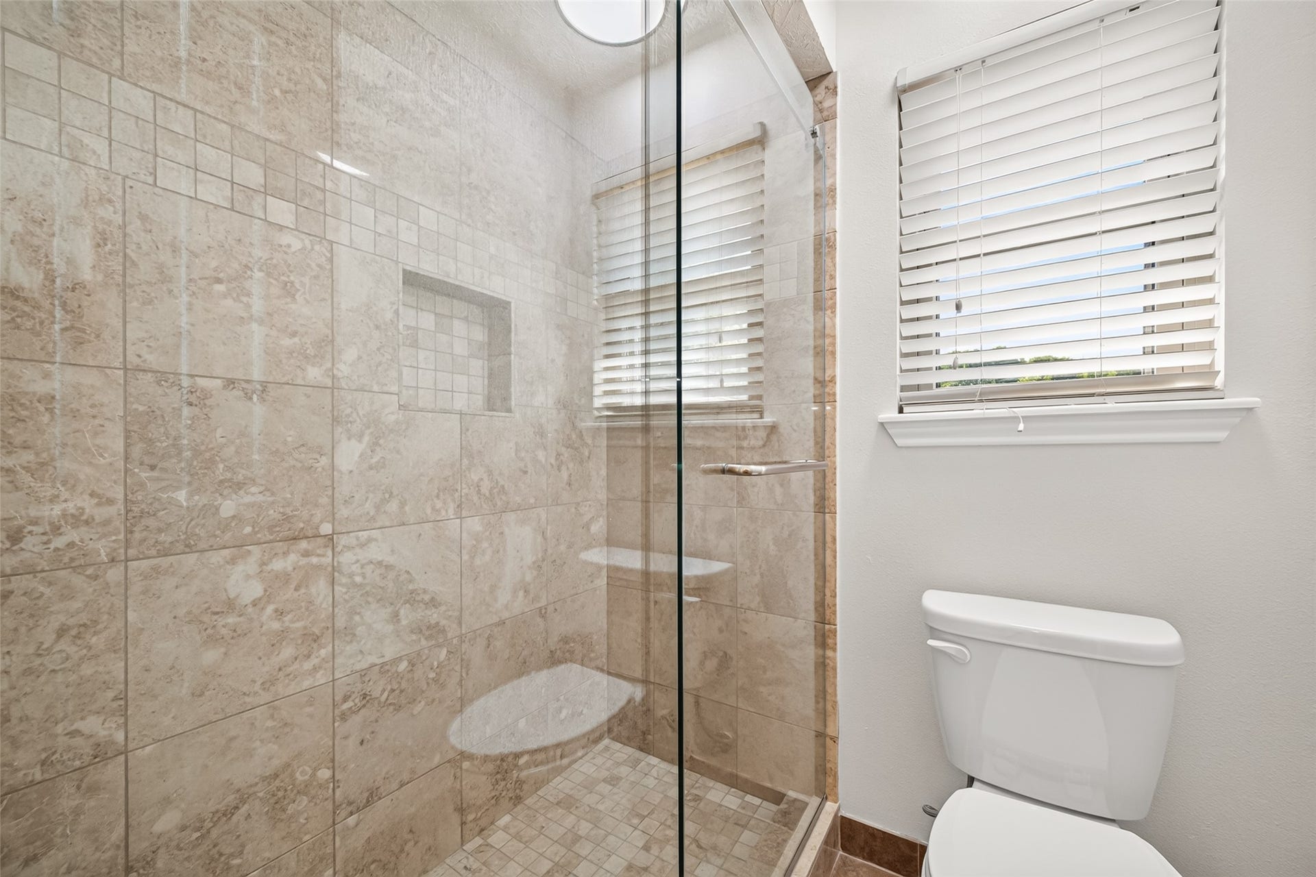PRIVATE ENCLOSED BATHING AREA! The upstairs full bathroom features a separate bathing area with an updated walk-in shower. Beautiful floor-to-ceiling tile, a decorative tile accent, built-in shampoo niche & glass shower enclosure create an attractive, functional space. A window with blinds brings in natural light. This practical design allows multiple people to get ready for the day at the same timemaking busy mornings a little  simpler.