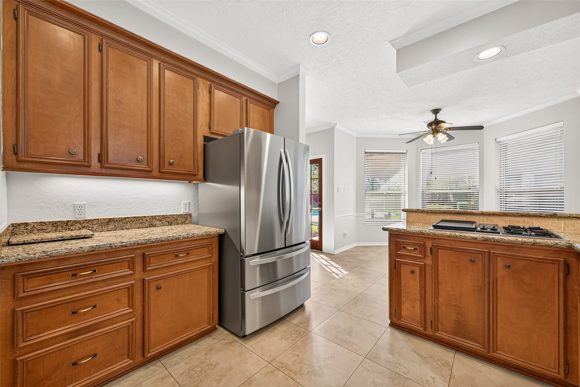 BEAUTIFUL AND SO ACCOMMODATING! This view showcases additional cabinetry, counter space & the LG Cafe refrigerator with convenient interior ice & water dispensers. With both doors open, the shelves can accommodate serving traysideal when entertaining! Just beyond the kitchen is the cheerful breakfast area, where windows invite natural light inside. Picture starting your morning with a cup of coffee, checking the day's schedule or enjoying a casual meal together with the family before heading out the door.