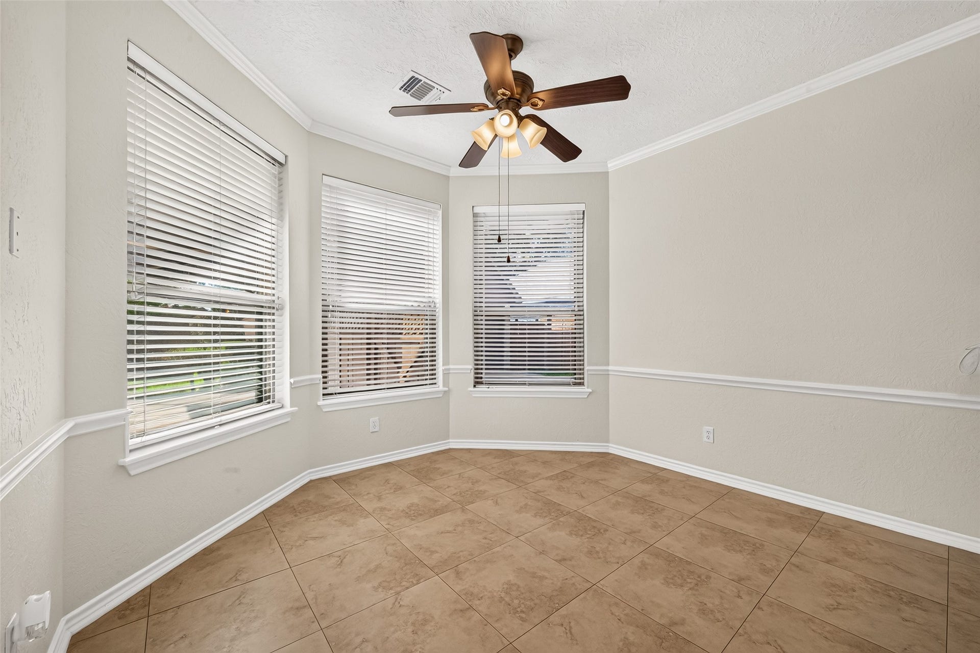 SUNSHINE AND BACKYARD VIEWS! This cheerful breakfast area is filled with natural light from beautiful bay windows overlooking the backyard & swimming pool. What a convenient spot to enjoy everyday meals while keeping an eye on the kids playing outside! Crown & chair-rail molding add a touch of traditional charm, while 2-inch blinds offer privacy & light control. A ceiling fan keeps the air circulating as you enjoy breakfast, an afternoon snack or a leisurely weekend brunch. Enjoy the view!