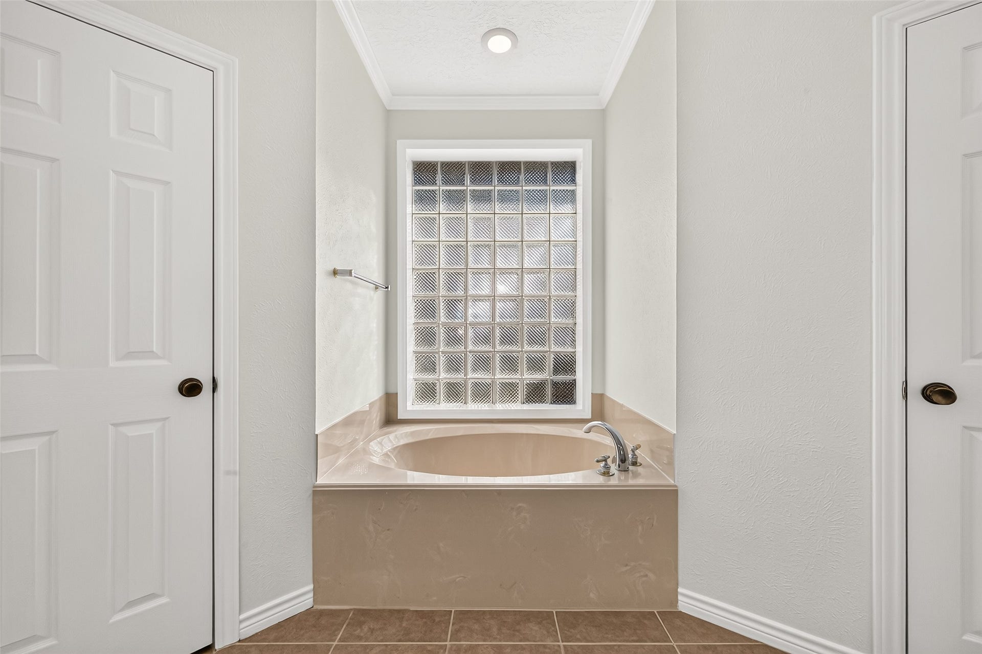 A LITTLE TIME TO SOAK & UNWIND! At the end of a long day, imagine enjoying a relaxing soak in the deep garden tub. The beautiful glass-block window allows natural light to filter into the bathroom while maintaining privacy. Crown molding adds a traditional finishing touch, while the doors on either side lead to TWO lighted walk-in closetsproviding convenient storage for organizing clothing, shoes & accessories. No need to share closets now!