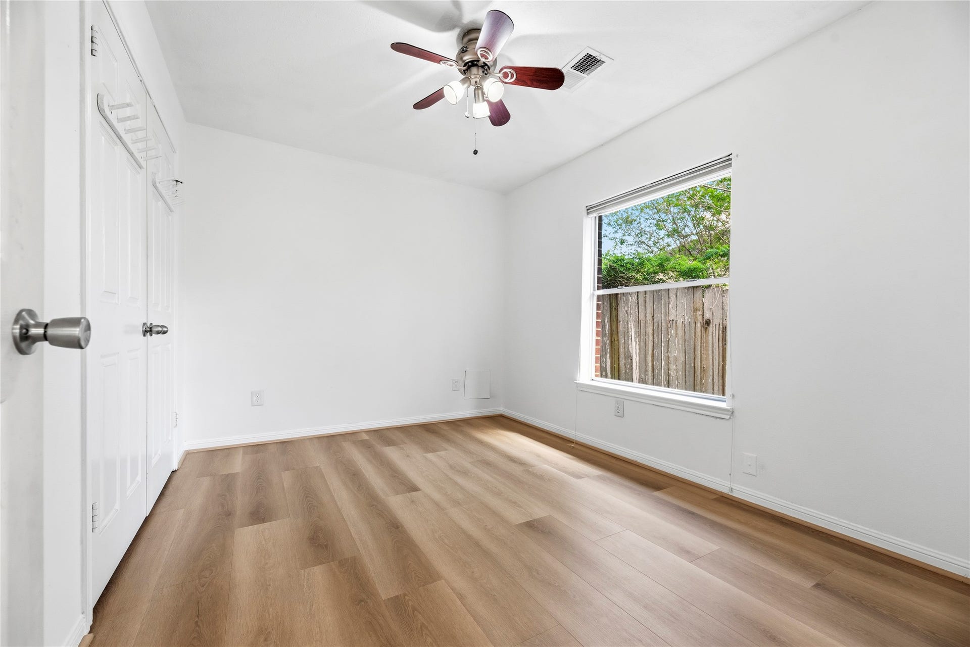 Secondary bedroom complete with wide plank LVP floors, large window, and ceiling fan.