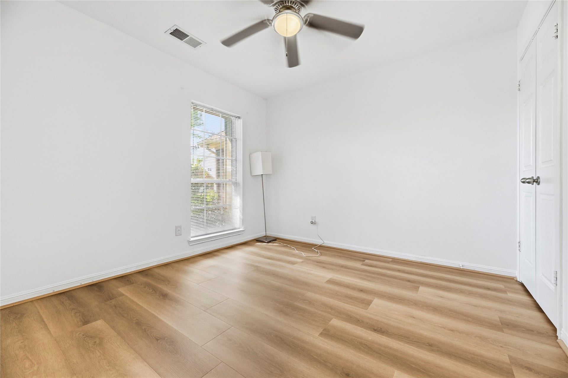 Secondary bedroom complete with wide plank LVP floors, large window, and ceiling fan.