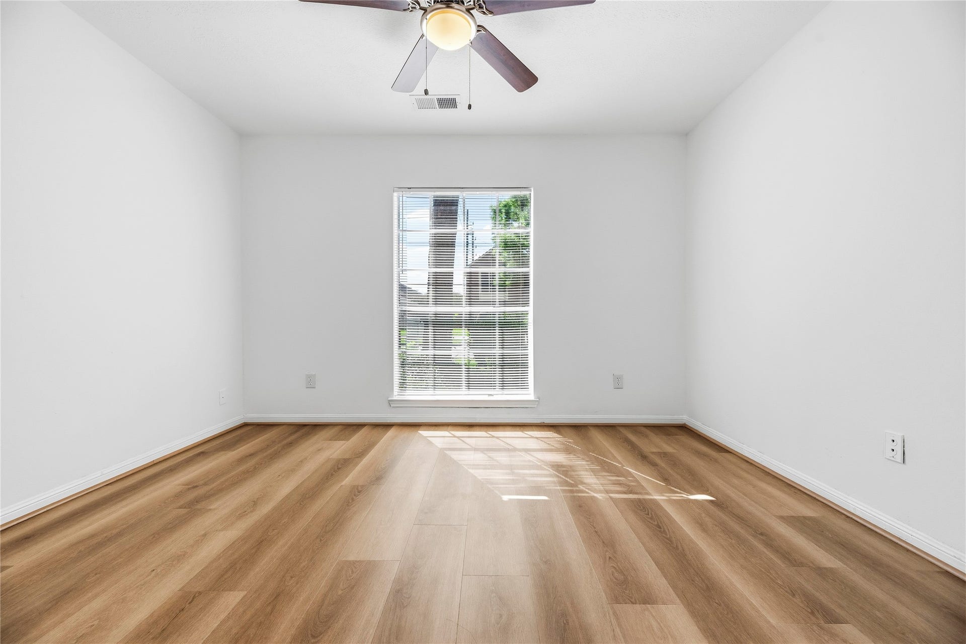 Secondary bedroom complete with wide plank LVP floors, large window, and ceiling fan.