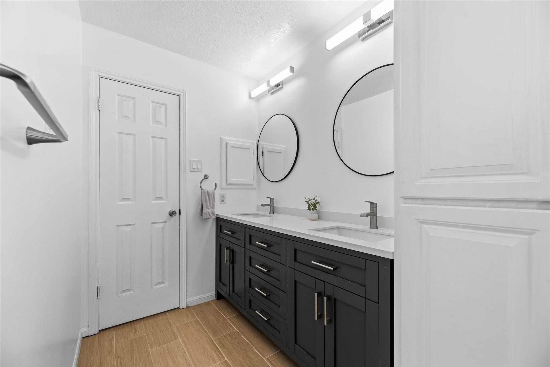 Primary en-suite featuring dual sinks, sleek floors, modern fixtures, and a large soaking tub + walk in shower.
