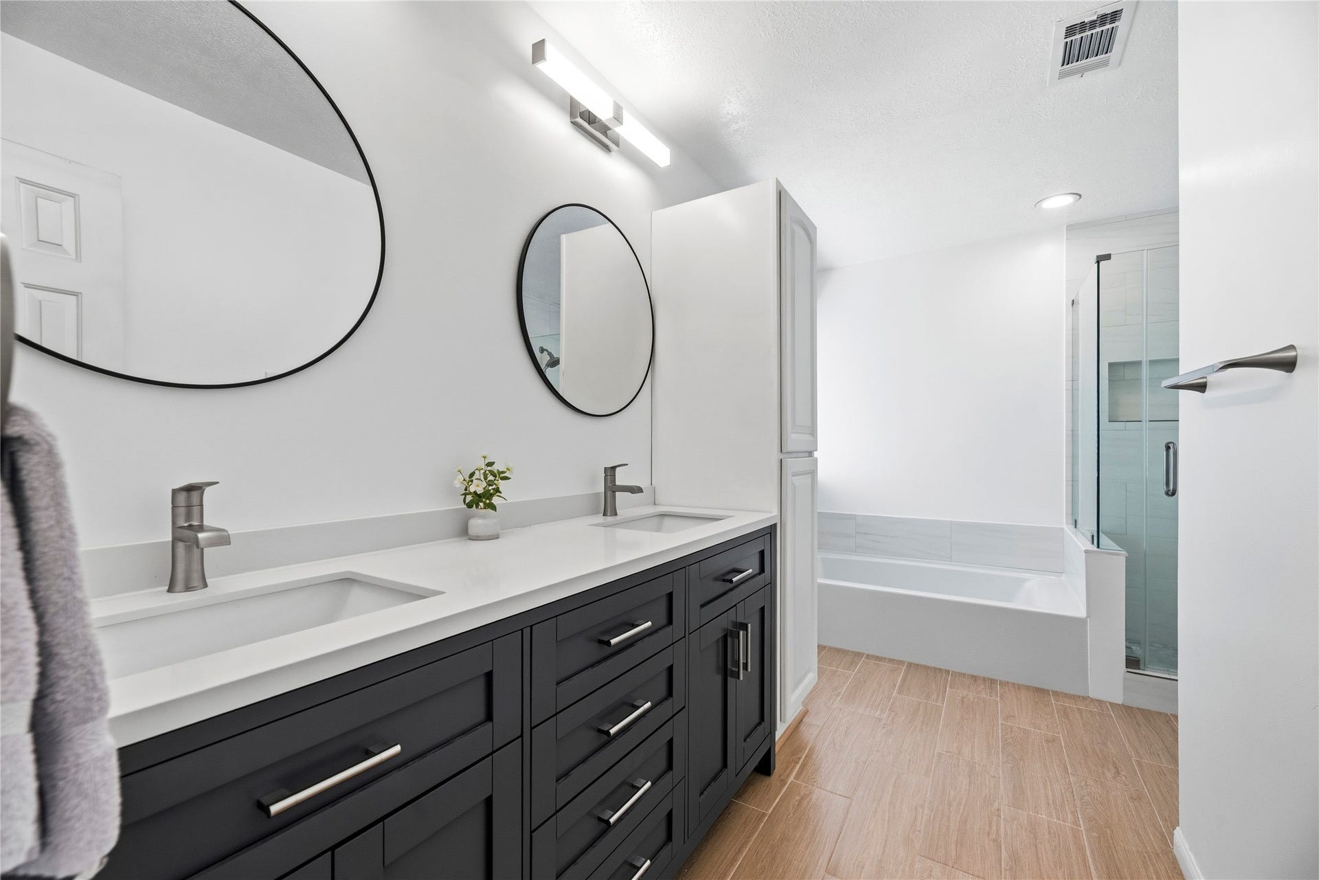 Primary en-suite featuring dual sinks, sleek floors, modern fixtures, and a large soaking tub + walk in shower.
