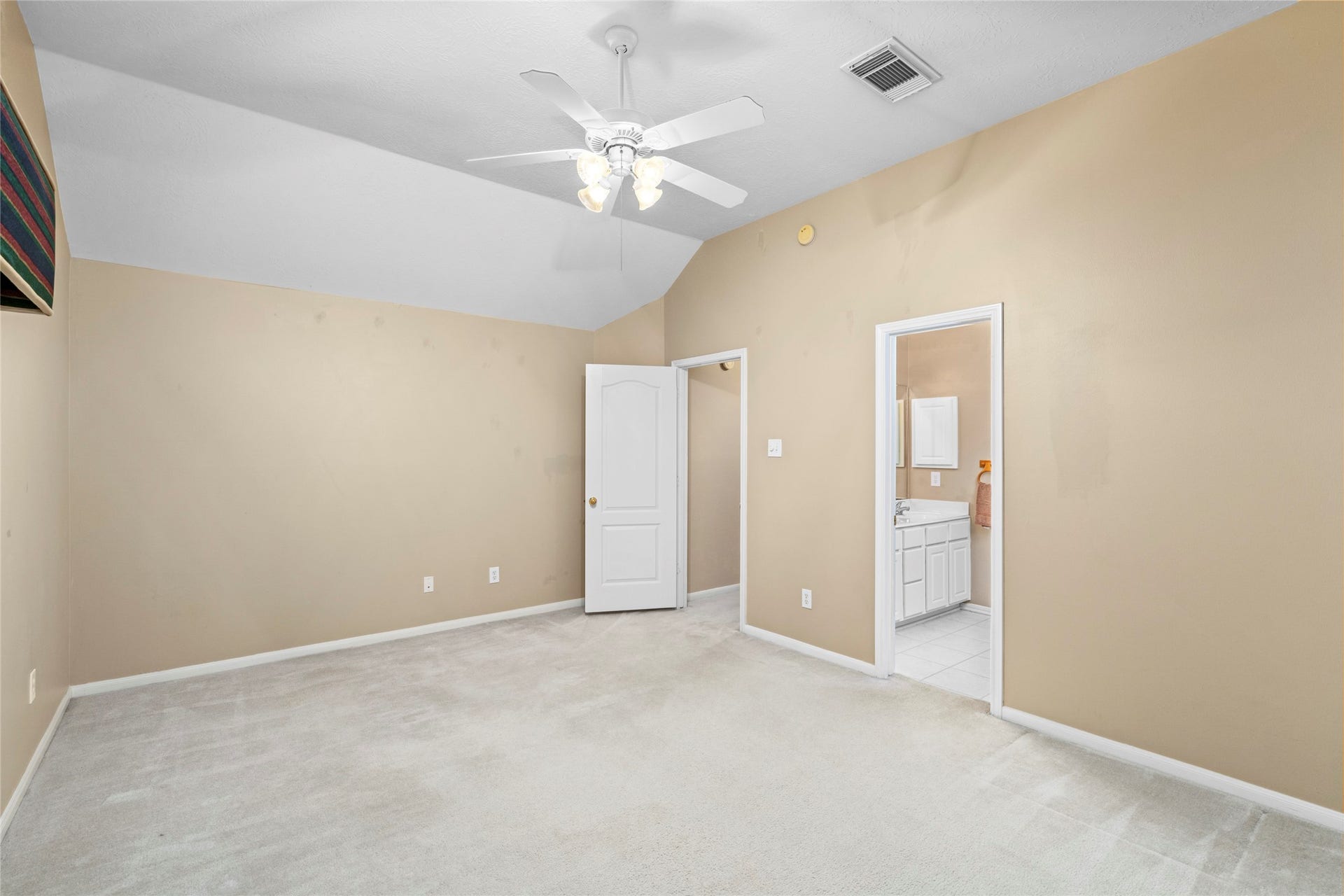 Spacious bedroom with neutral finishes, carpeting, ceiling fan, and convenient en-suite bath access. The combination of privacy and functionality makes this room especially appealing for a secondary suite, guest room, or family member seeking additional independence.