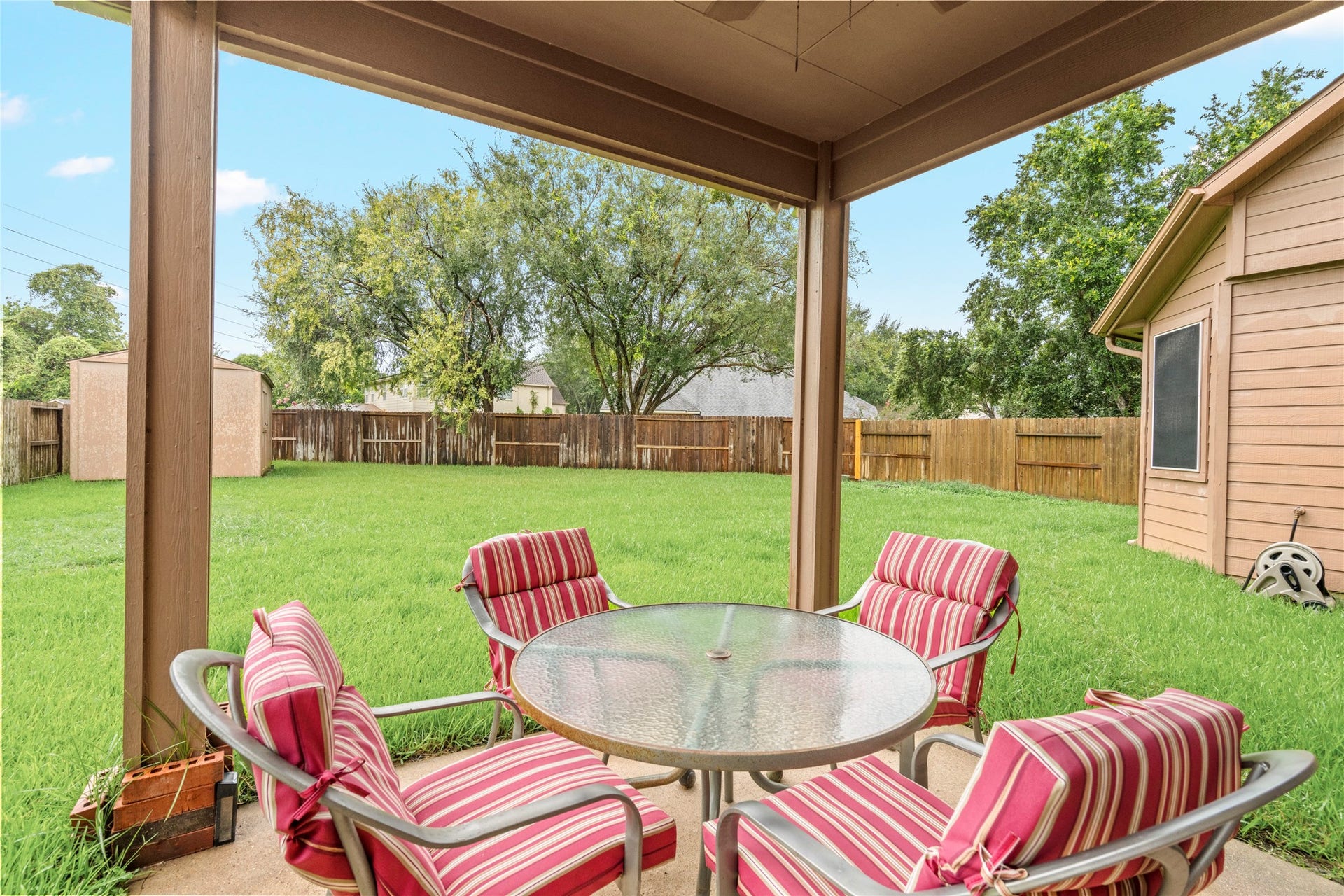 Rear patio view emphasizing the covered outdoor area and generous lawn beyond. The layout offers buyers a ready-made foundation for creating an inviting outdoor entertaining area without sacrificing usable yard space.