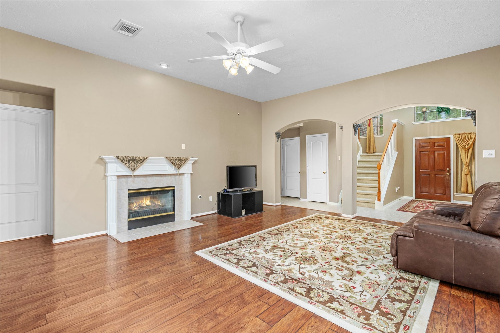 Spacious main living room centered around a gas fireplace and framed by distinctive archways. The combination of generous space, natural light, and a focal-point fireplace creates the kind of gathering area buyers look for when envisioning comfortable everyday living.