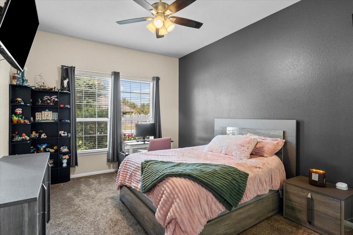 4329 S Meridian Greens Drive, Dickinson, TX 77539 Secondary bedroom with accent wall, ceiling fan, and a bright window.