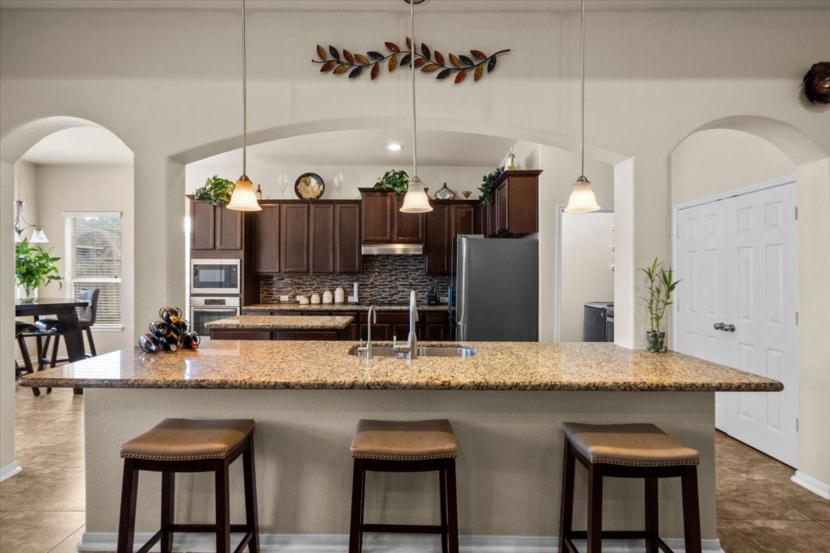 4329 S Meridian Greens Drive, Dickinson, TX 77539 Oversized granite breakfast bar with seating for casual meals.