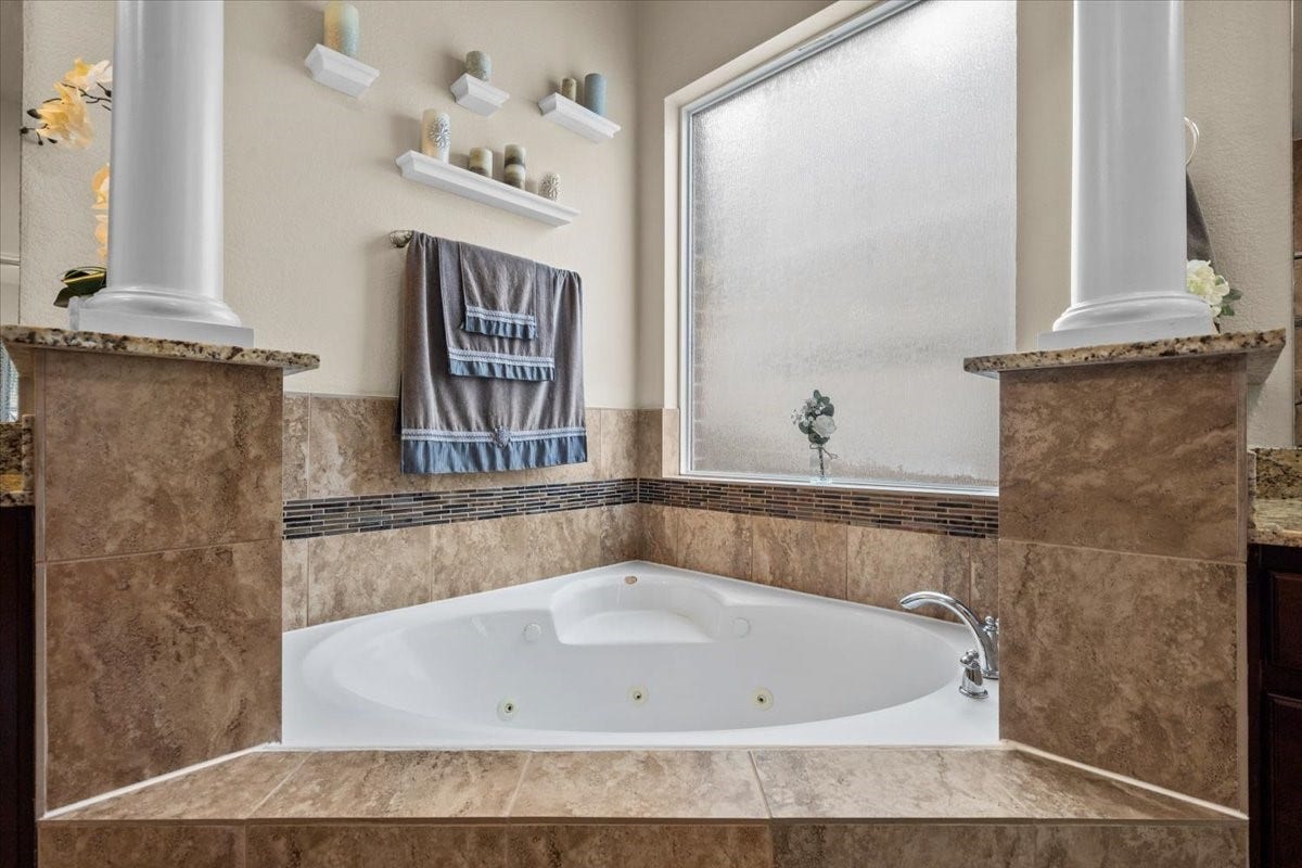 4329 S Meridian Greens Drive, Dickinson, TX 77539 Corner soaking tub framed by columns for a spa-like retreat.