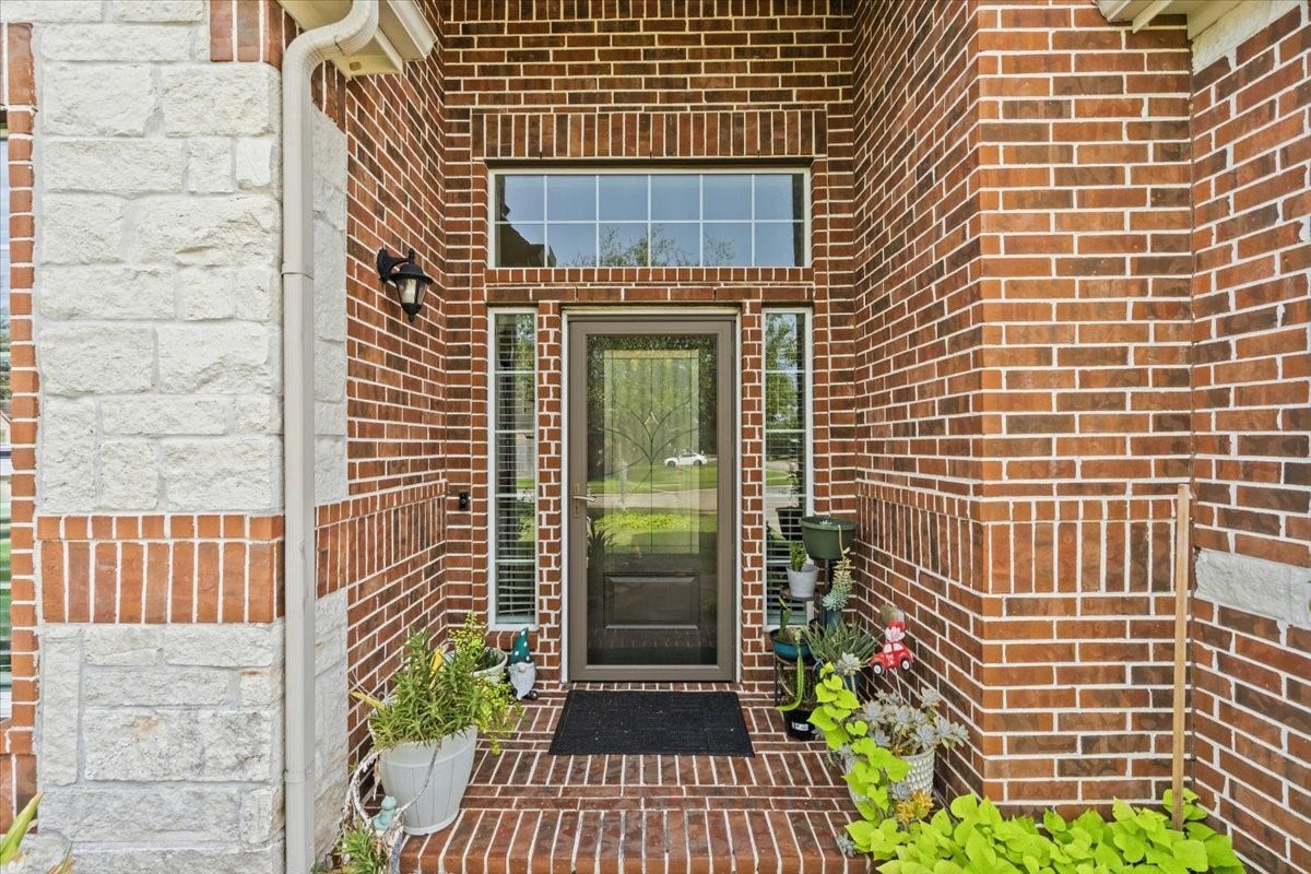 4329 S Meridian Greens Drive, Dickinson, TX 77539 Charming covered front entry with brick and stone detail and a glass front door.