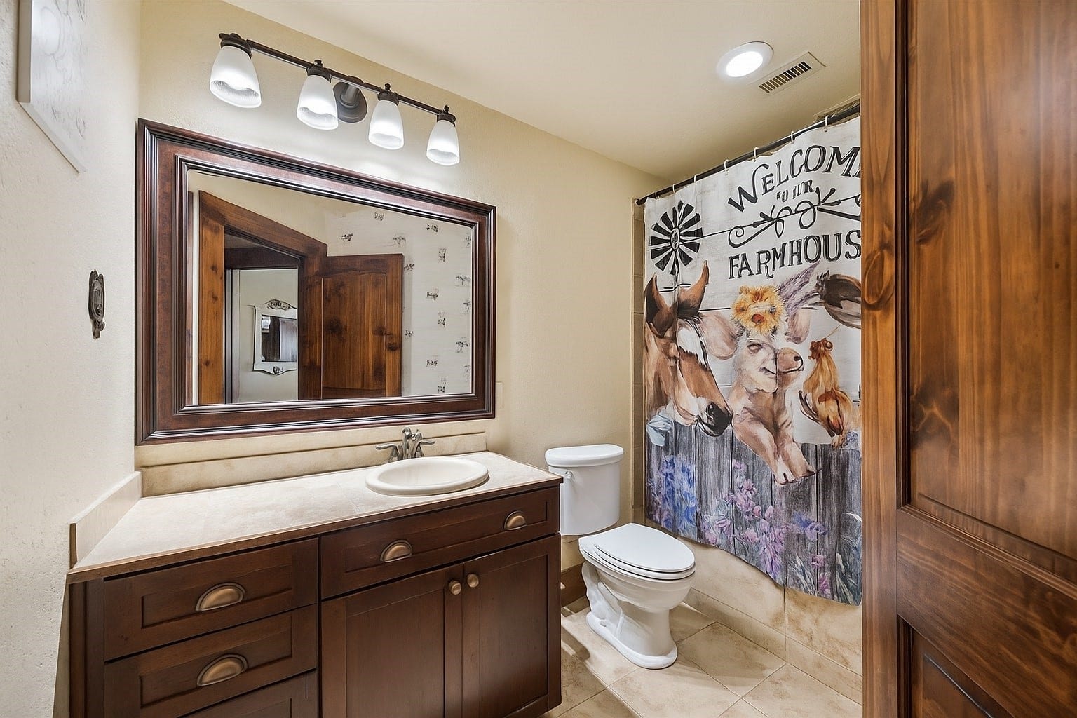 Charming and whimsical, this full bathroom blends rustic farmhouse personality with practical design. The vintage vanity and oversized framed mirror create a space that feels both fun and functional.