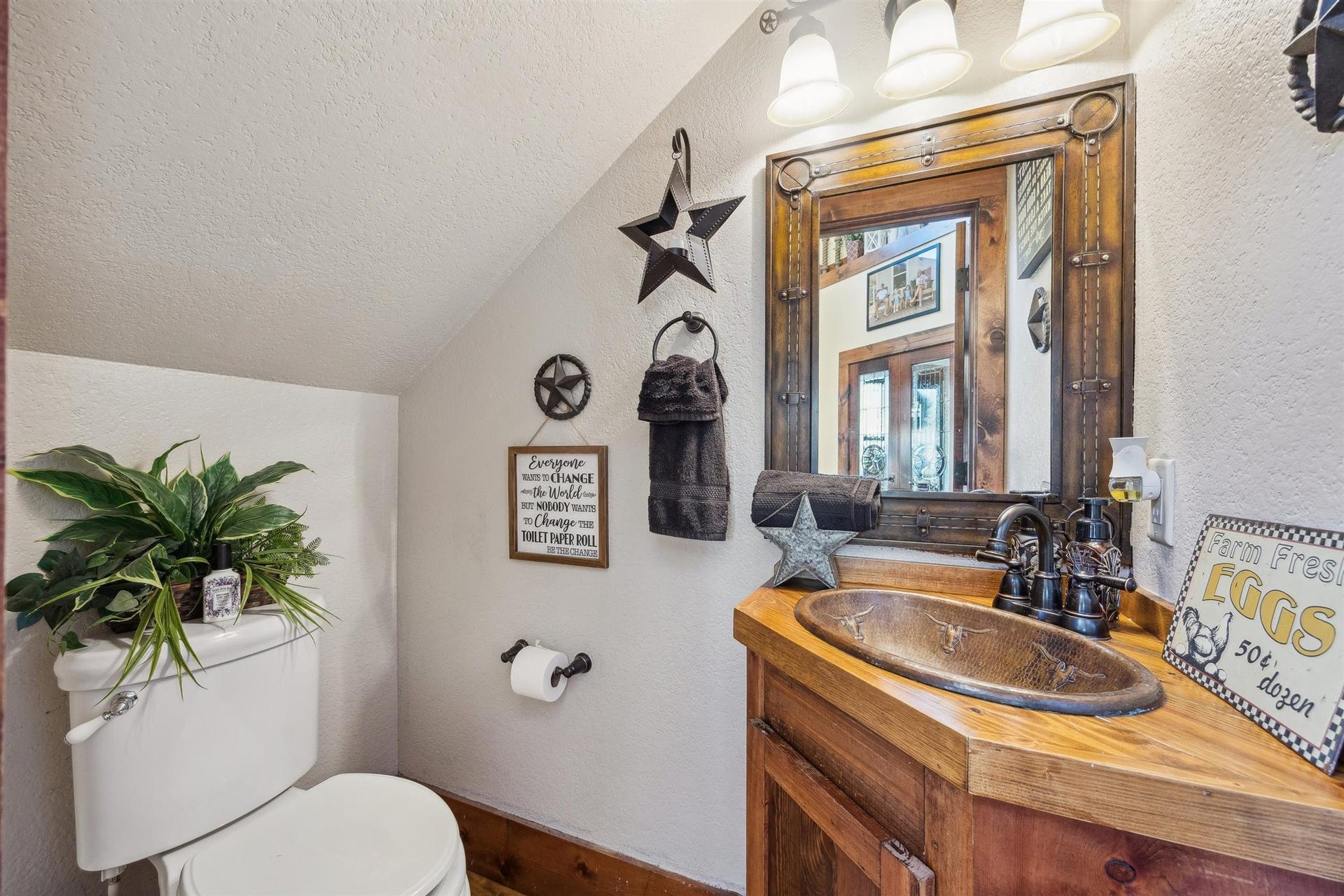 This cozy half-bath is filled with rustic character from the copper-toned sink basin to the star-accented mirror and Texas-themed decor. Tucked conveniently beneath the stairs, its both functional and full of flair, ideal for guests and everyday use.