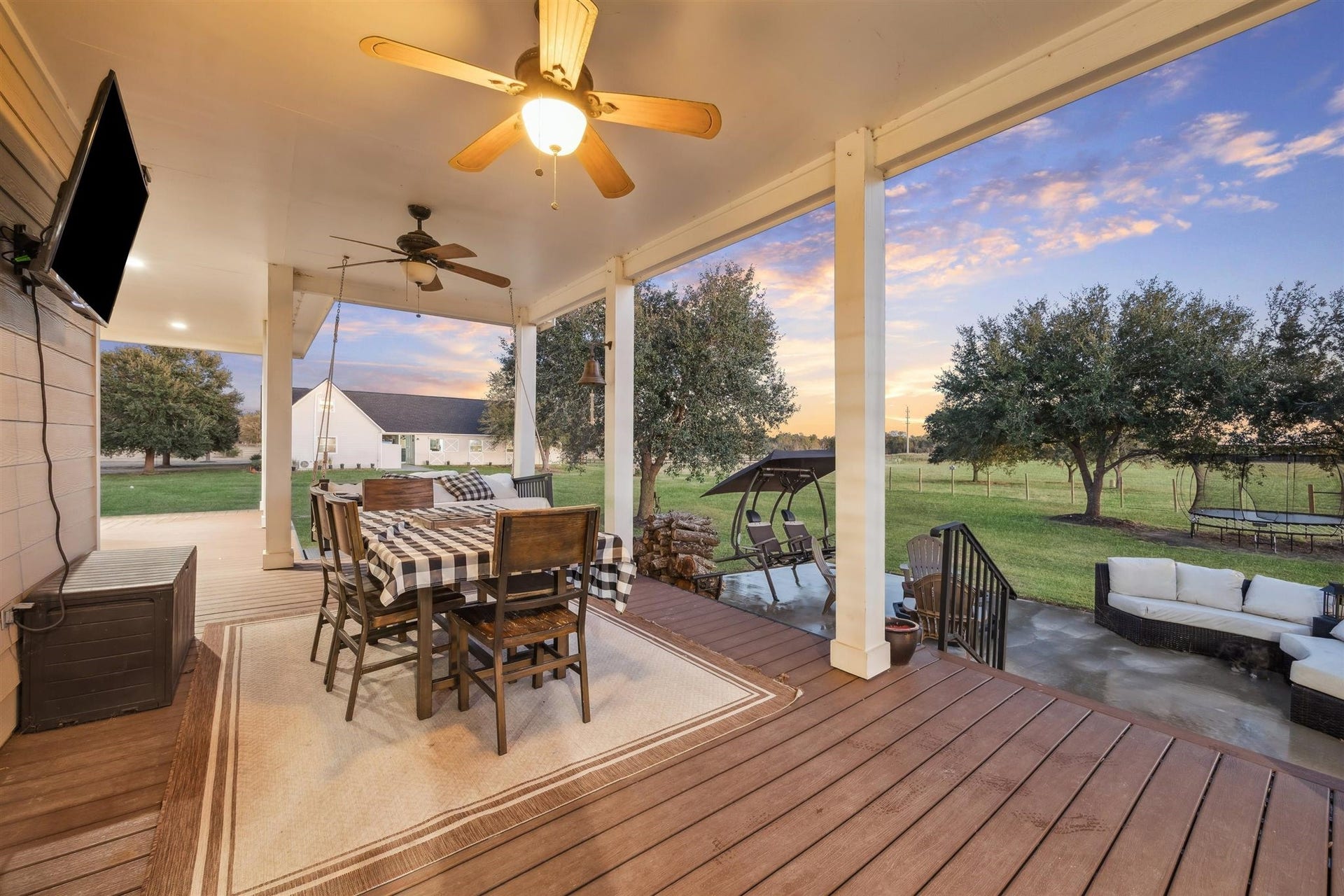 This covered deck doubles as an open-air dining room, complete with overhead fans, rustic string lights, and a checkered tablecloth that adds down-home flair. Steps away from the yard, it invites meals under the stars and breezy mornings with a view.