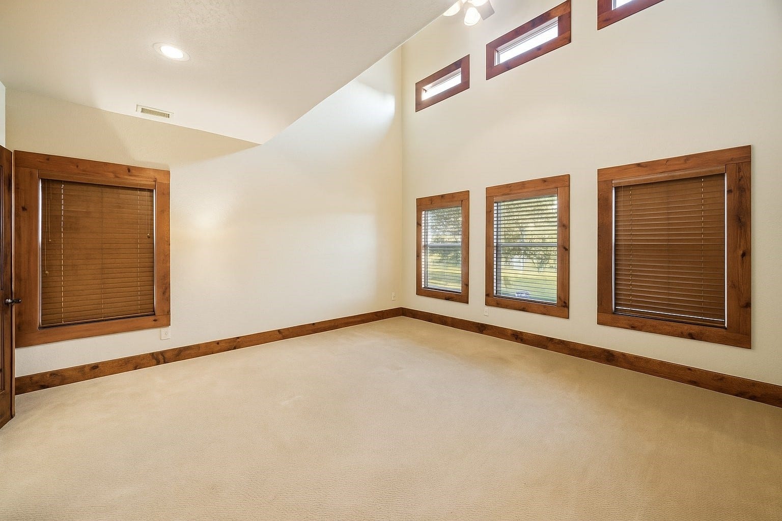 Retreat to a true Texas-style primary suite with soaring ceilings, custom wood furnishings, and peaceful pasture views. Light floods through high-set clerestory windows and three full-sized windows, creating a warm and tranquil space. Virtually decluttered to help visualize potential use.