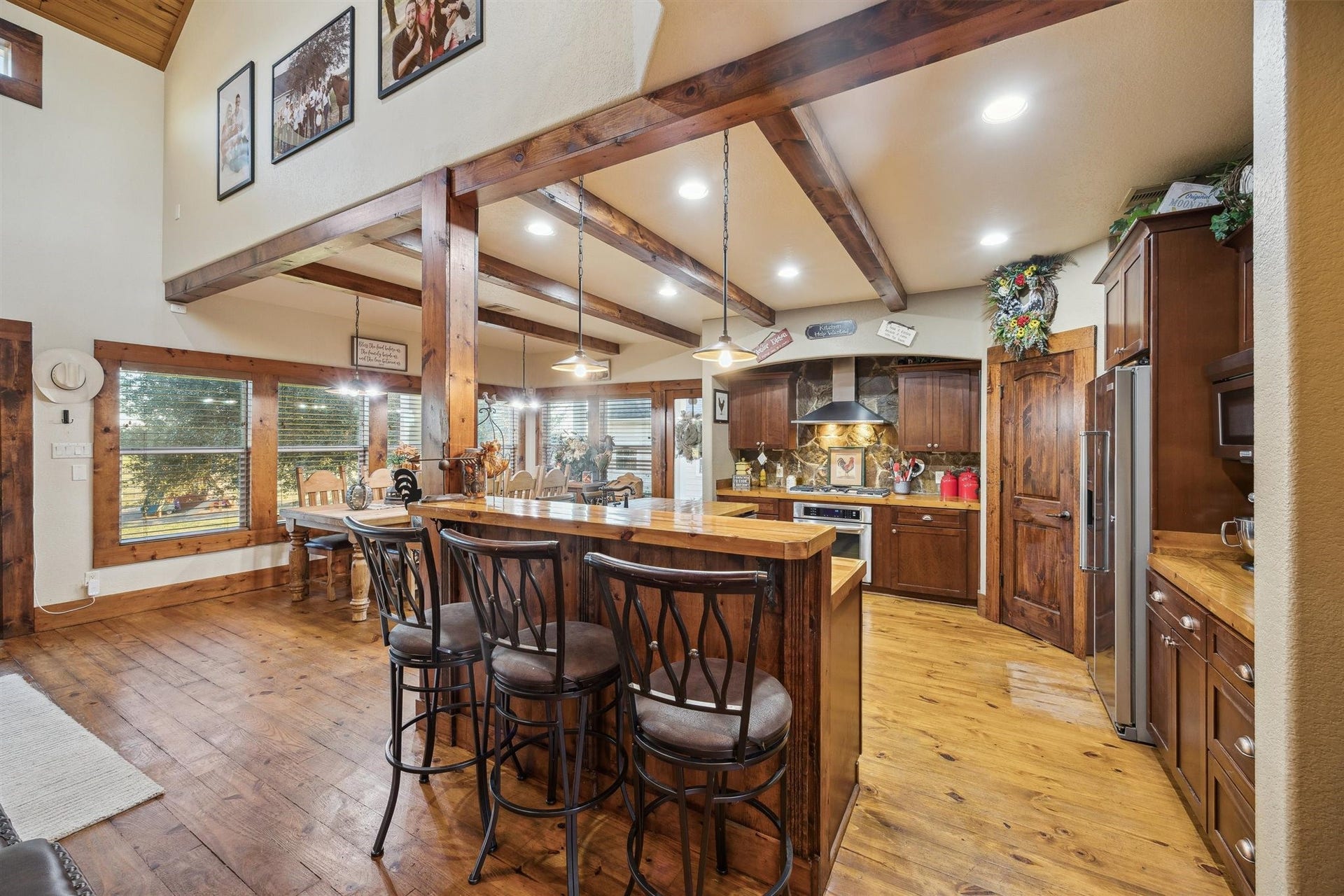 Country elegance meets modern function in this chefs kitchen. With rich cabinetry, exposed beams, bar seating, and pendant lighting, the space invites gathering and good meals. Every inch is designed for hosting and comfort.