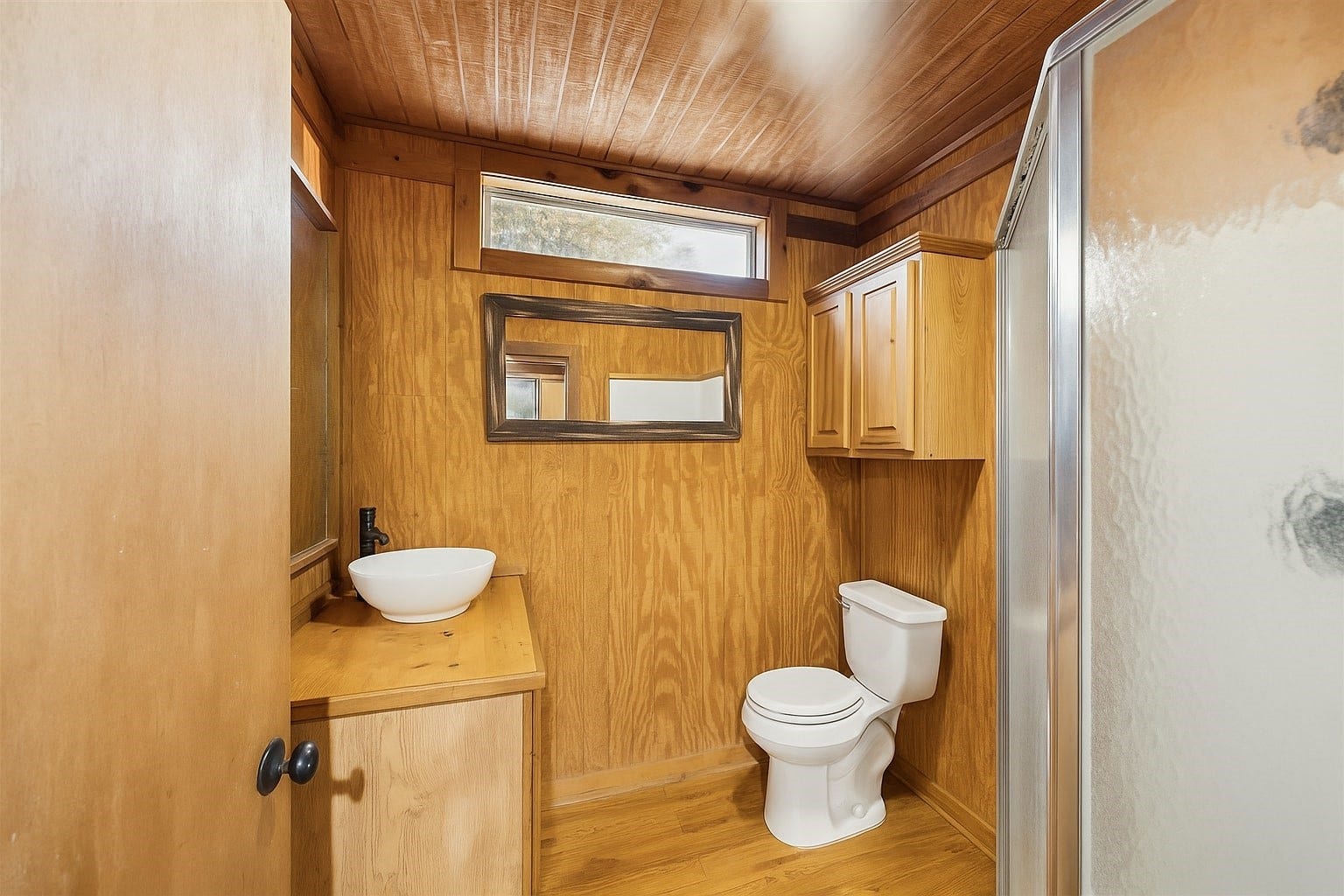 Cozy and well-equipped, this full guest bathroom features a walk-in shower, custom wood cabinetry, and natural textures that echo the homes country aesthetic. A practical and private space for guests or multi-generational living.